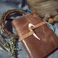 دفتر چرمی عاج، چرم گاوی افکتی فندقی رنگ، عاج چوبی دست‌ساز (چوب بلوط) 19/5 در 14 ، 120 برگ کاغذ نخودی رنگ