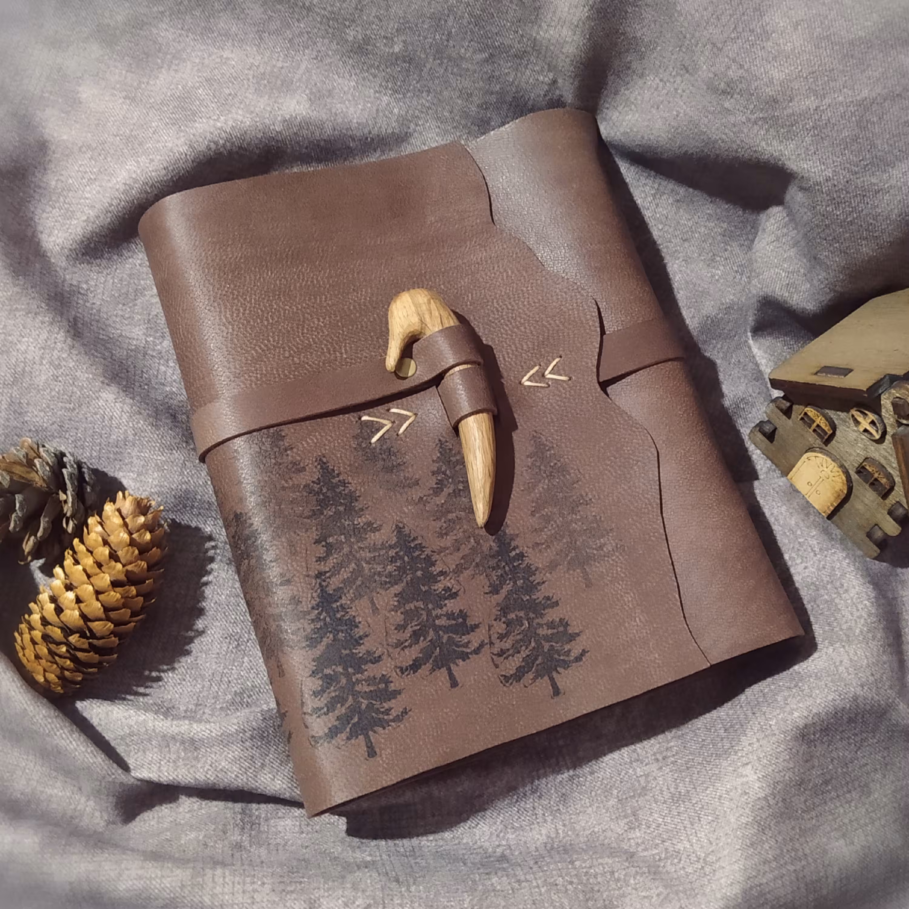 کلاسور چرمی کوهستان کاج، 21 در 16 ، چرم بزی خاکی رنگ، همراه صد برگ کاغذ نخودی خطدار، حک جنگل کاج، همراه بست شاخ چوب بلوط