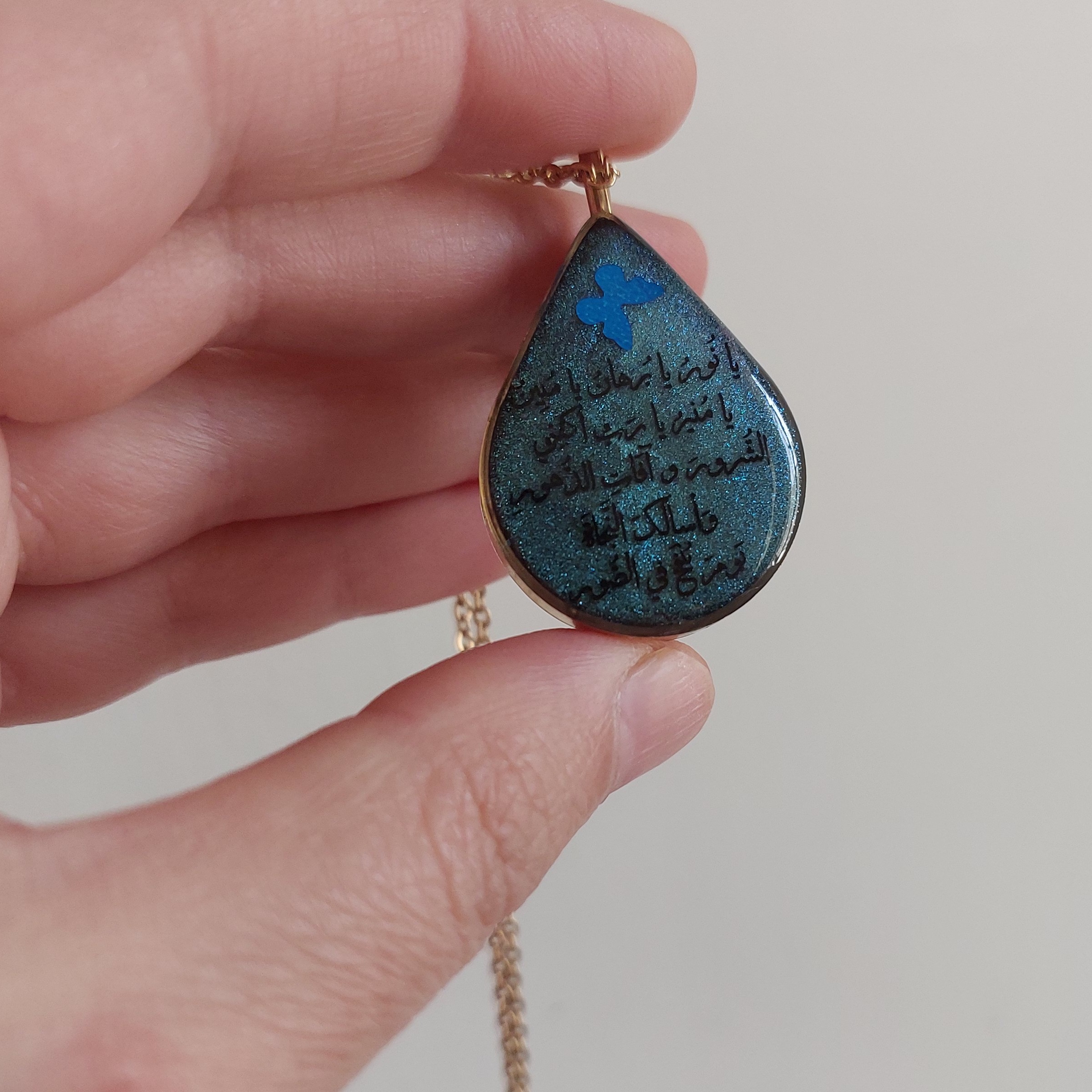 گردنبند رزینی مزین به وان یکاد و حرز امام جواد(ع) قاب برنجی اشکی و یراق آلات رنگ ثابت بسیار خوشرنگ و خاص