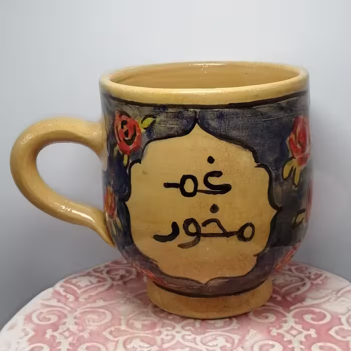 لیوان لعاب خورده با نقش و نگار و جمله غم مخور در یک سمت و زندگی کن در سمت دیگر 