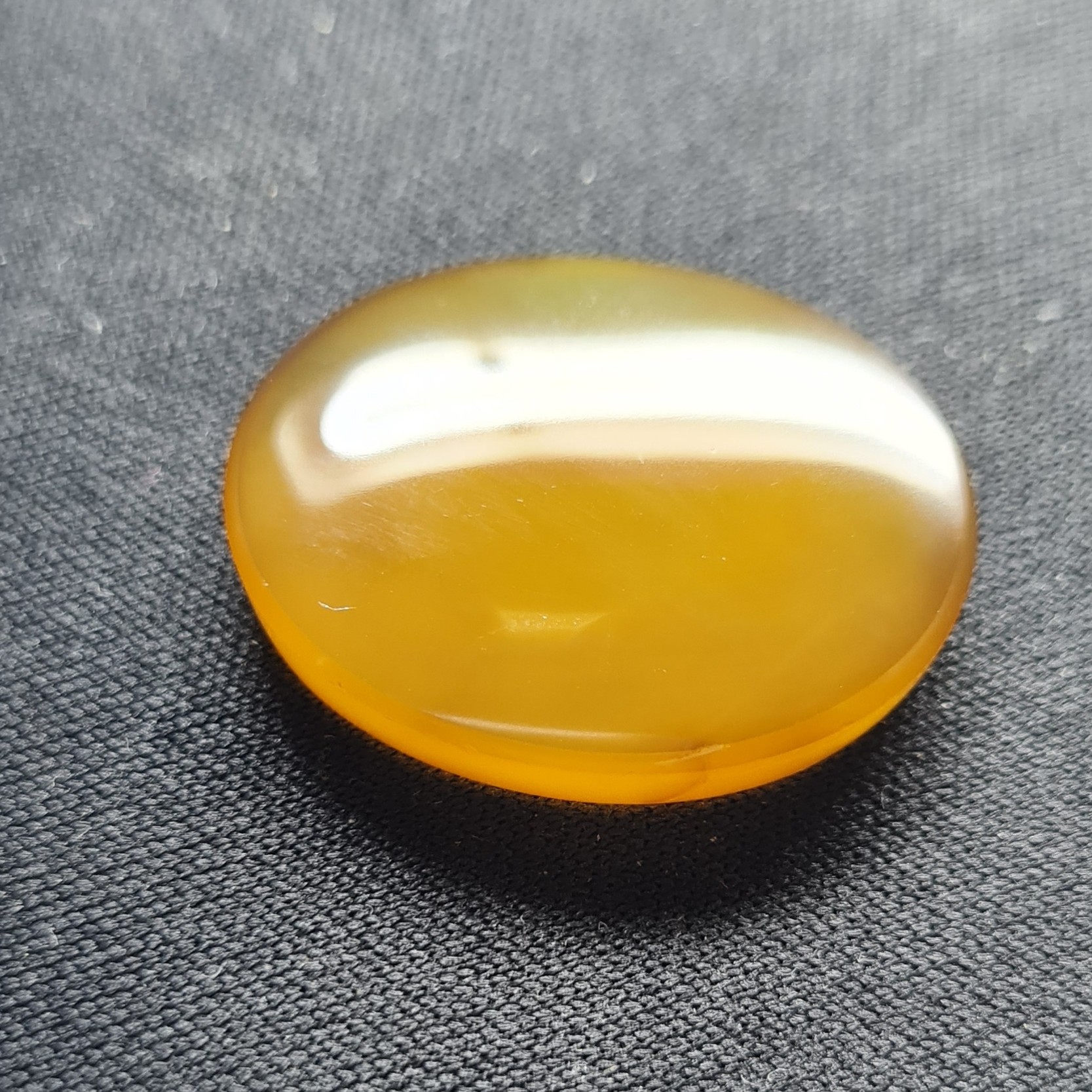 نگین عقیق زرد. مشخصات. طول 2.7 سانتی متر. عرض  2.2 سانتی متر. ارتفاع 0.5 سانتی متر.