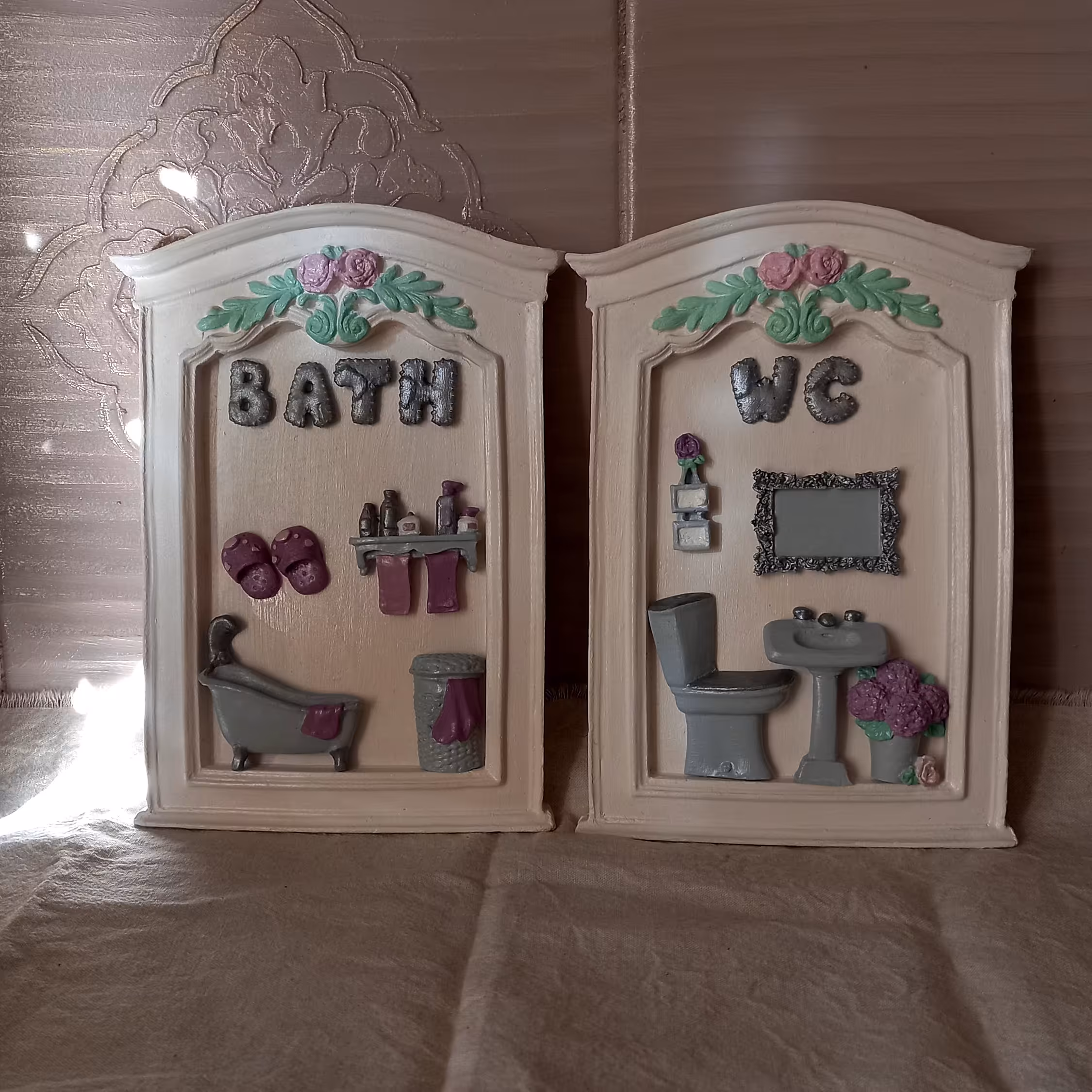 نشانگر حمام و دستشویی بازمینه صفحه ی سفید و طرح داخل آن ترکیب ازرنگ نقره ای