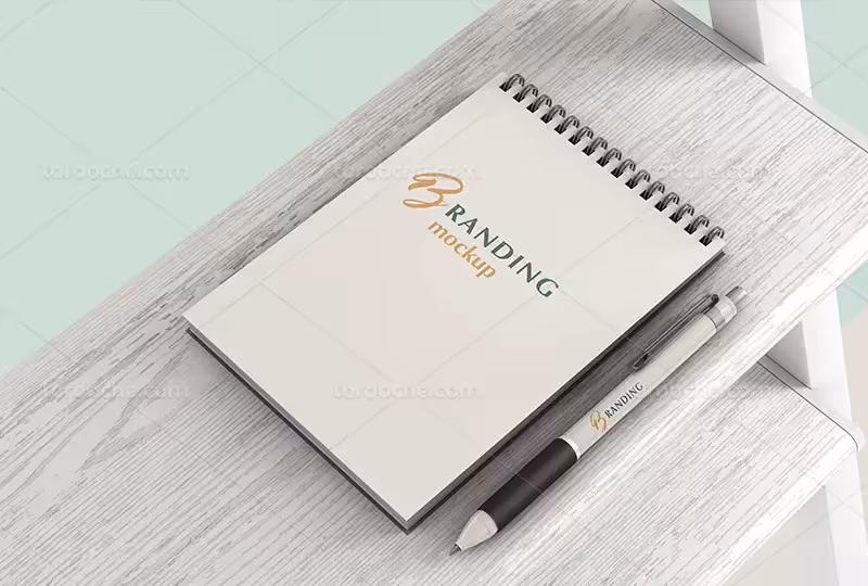 موکاپ دفترچه با خودکار روی میز چوبی | گرافیک با طعم تربچه