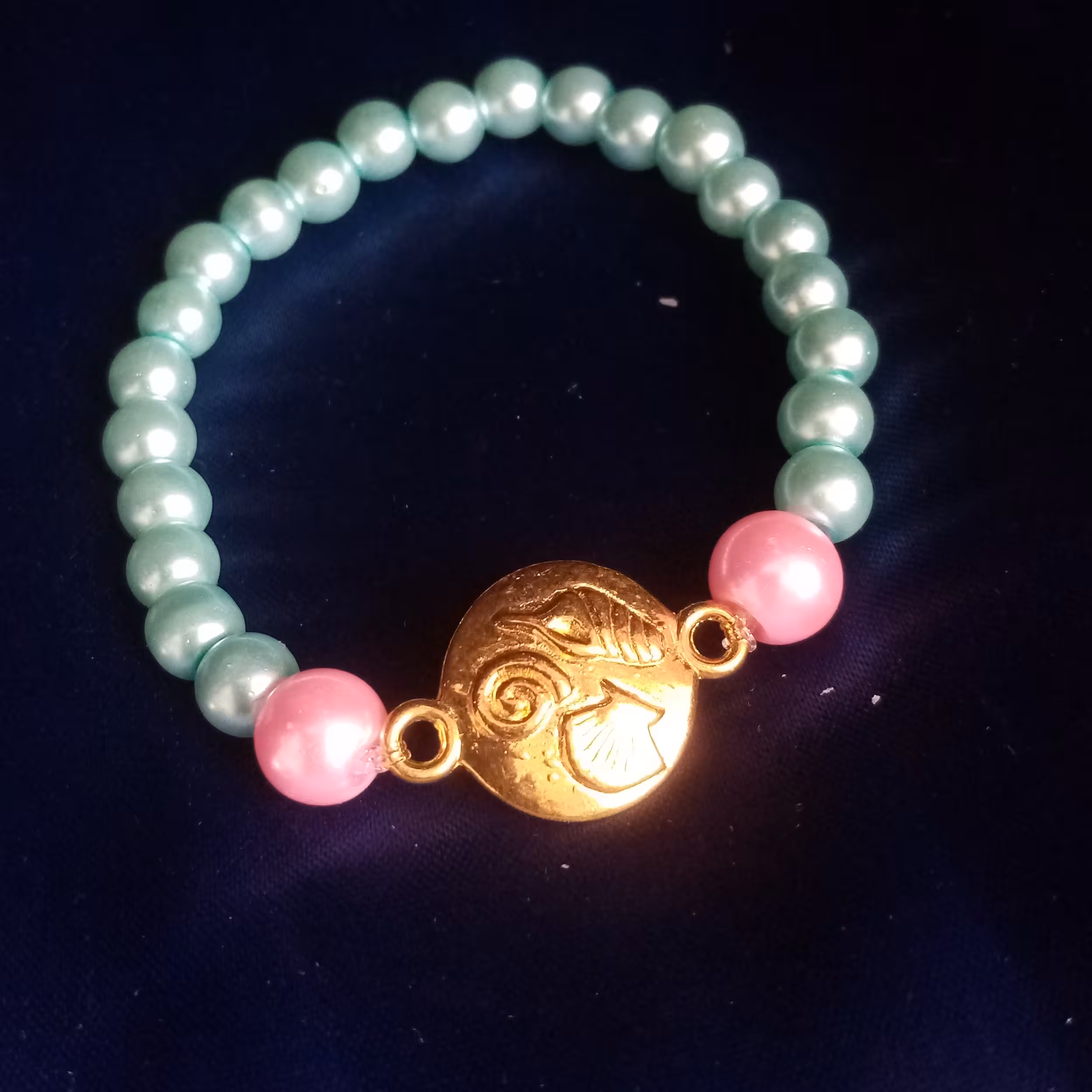 دستبند صدفی، این دستبند زیبا بایک علامت صدفی و مهره های آبی و صورتی درست شده است