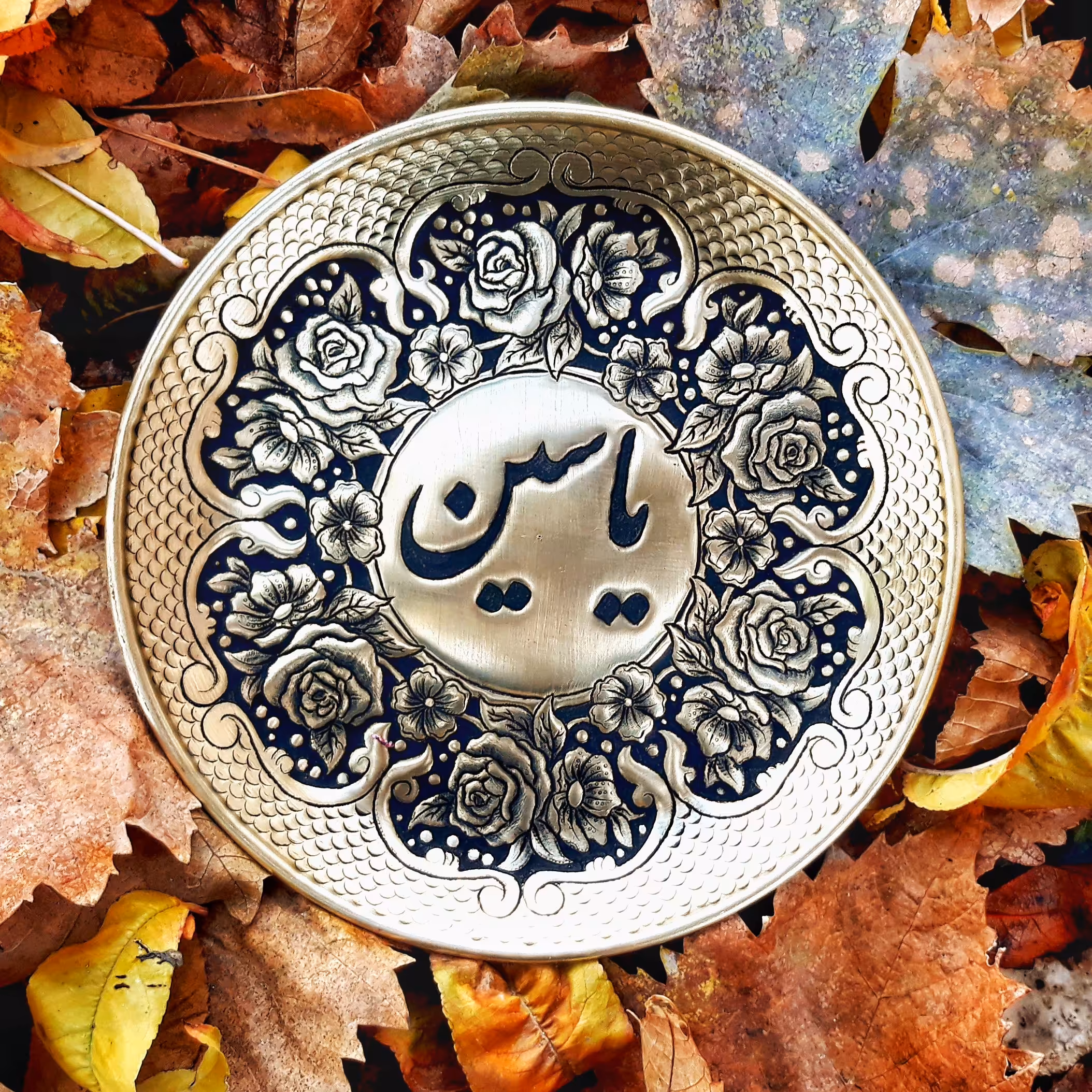 بشقاب قلمزنی شده ی اسم با حاشیه گل و بوته.این بشقاب از جنس برنج است اما شما میتدنید این کار رو روی مس هم سفارش بدین 