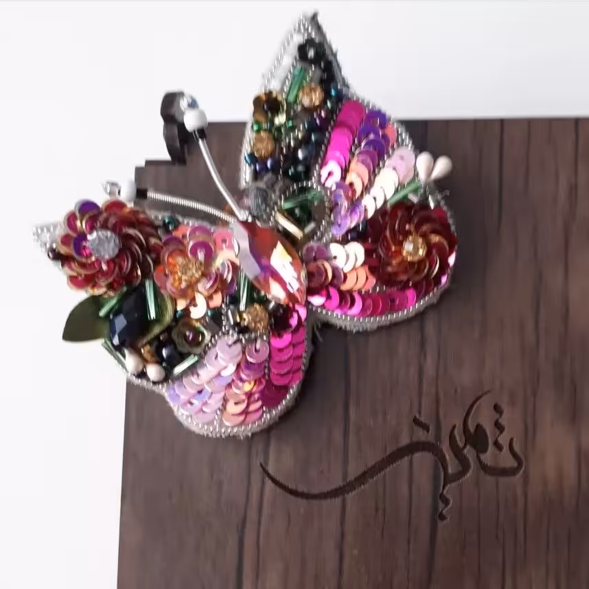 گلسینه طرح پروانه. از پشت چرم دوزی شده و به وسیله منجوق دور دوزی صورت گرفته همچنین با سوزن به لباس متصل میشود