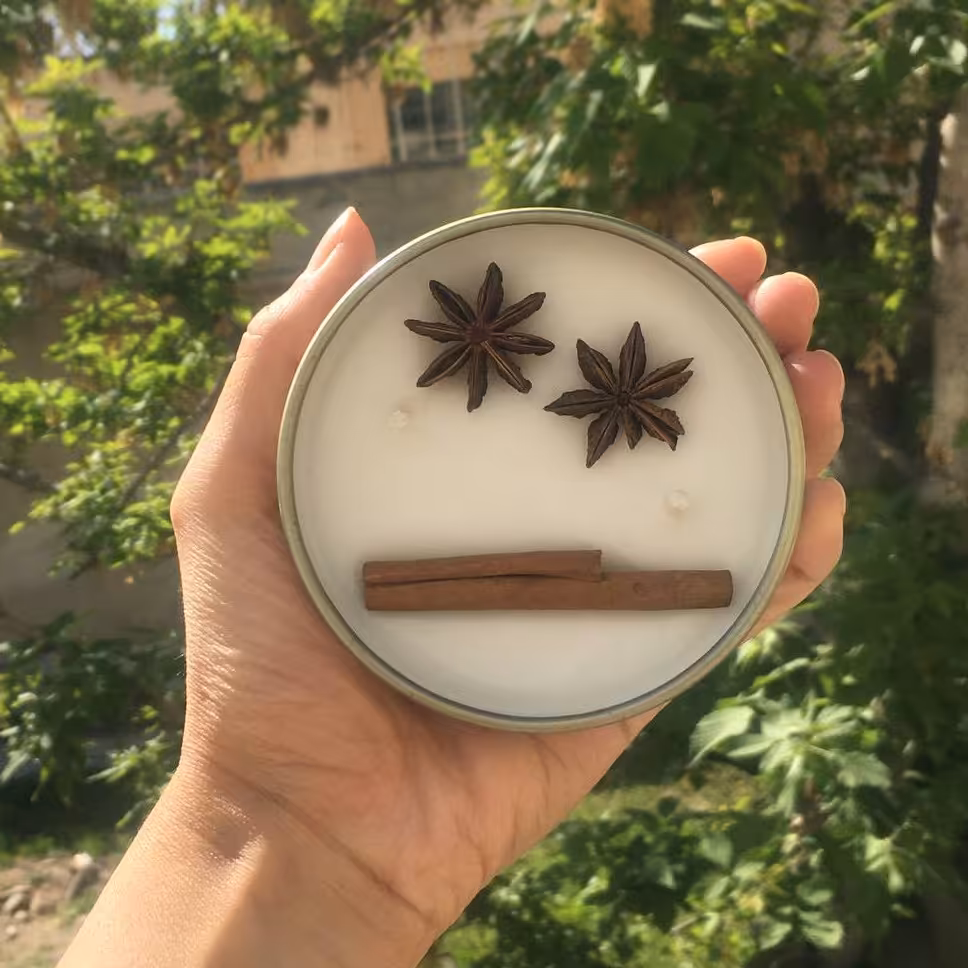 شمع قوطی فلزی درب دار رنگ طلایی تزیین شده با دارچین و بادیان ستاره ای