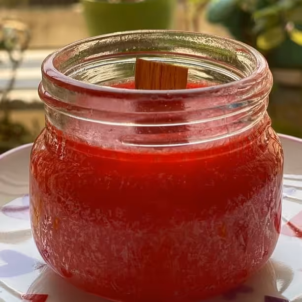 شمع گیاهی معطر  شیشه ای همراه با فیتیله چوبی رنگ قرمز . با رایحه دارچین.