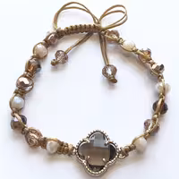 دستبند مدل نایت  کریستال با تناژ کرم و قهوه ای و بافت منحصر به فرد بین مهره ها همچنین پلاک طرح ونکلیف کریستالی شفاف تراش