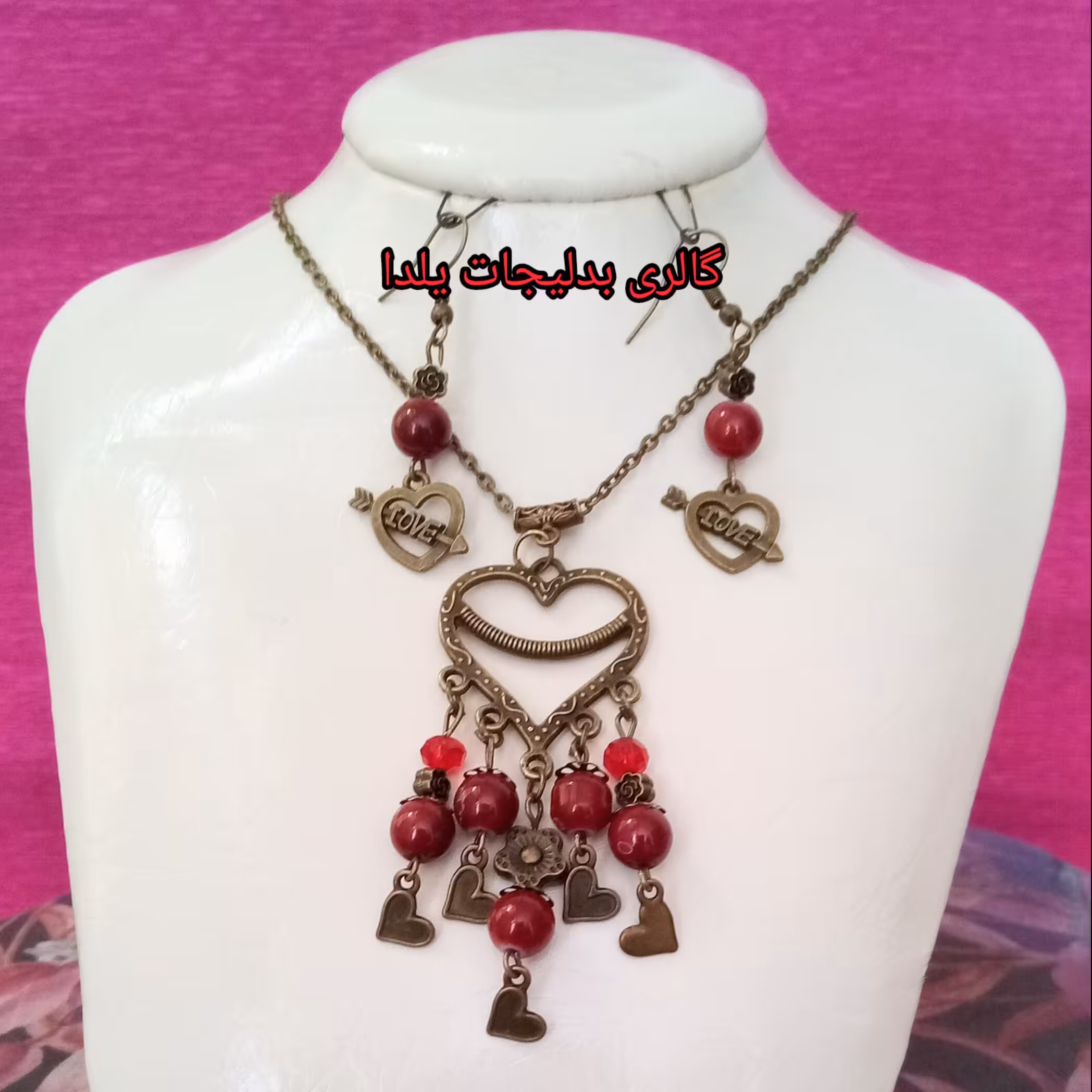 نیم ست قلبی شامل گردنبند و گوشواره با آویز قلبی و مهره های کریستالی قرمز