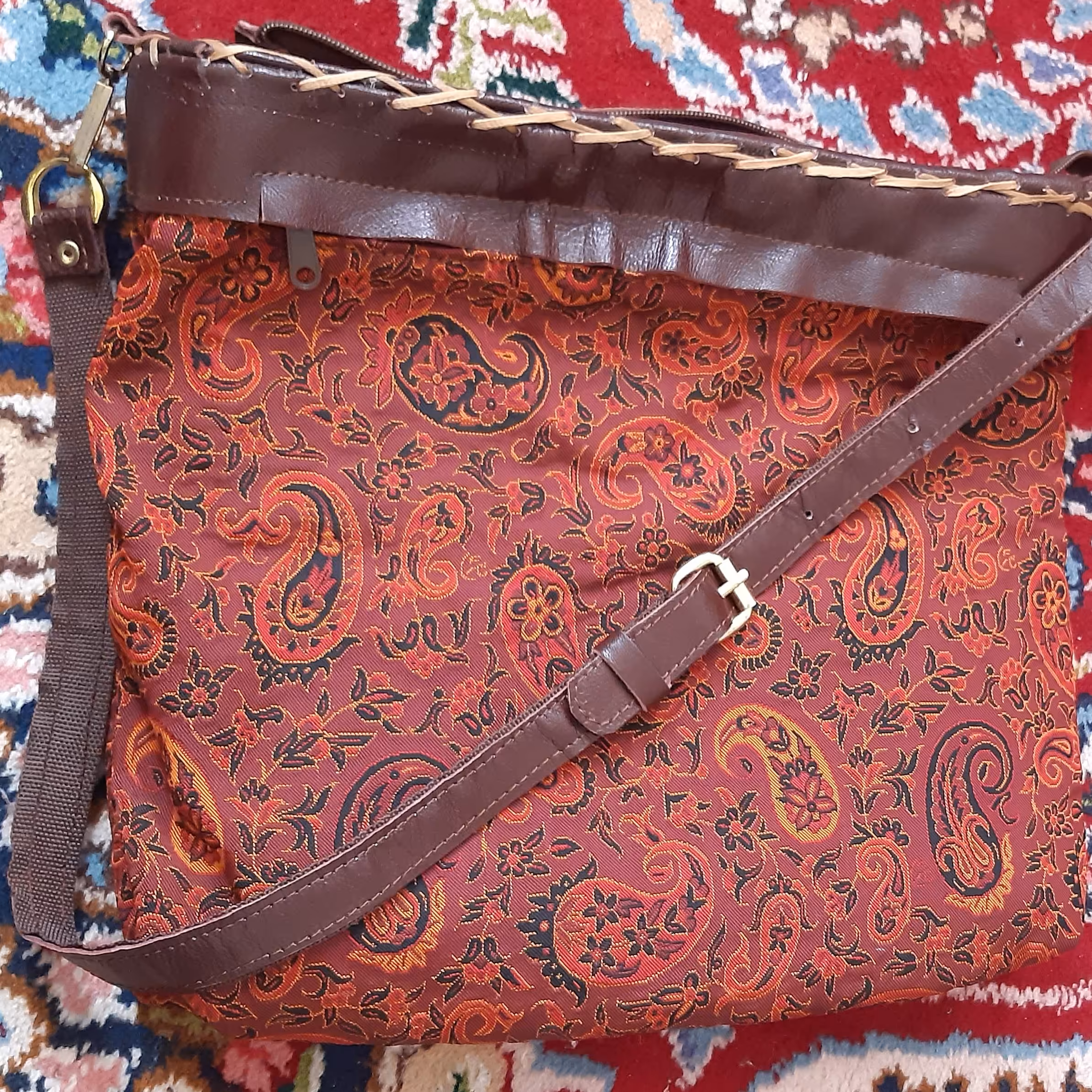 کیف چرم طبیعی وپارچه ترمه درابعاد30در30در8سانتیمتربابندپستچی زرشکی ویراق طلایی بایک جیب بزرگ بیرون ودو جیب کوچک داخل