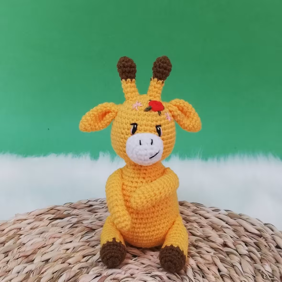 عروسک بافتنی زرافه کوچولوی نشسته با گلای قشنگ رو سرش
