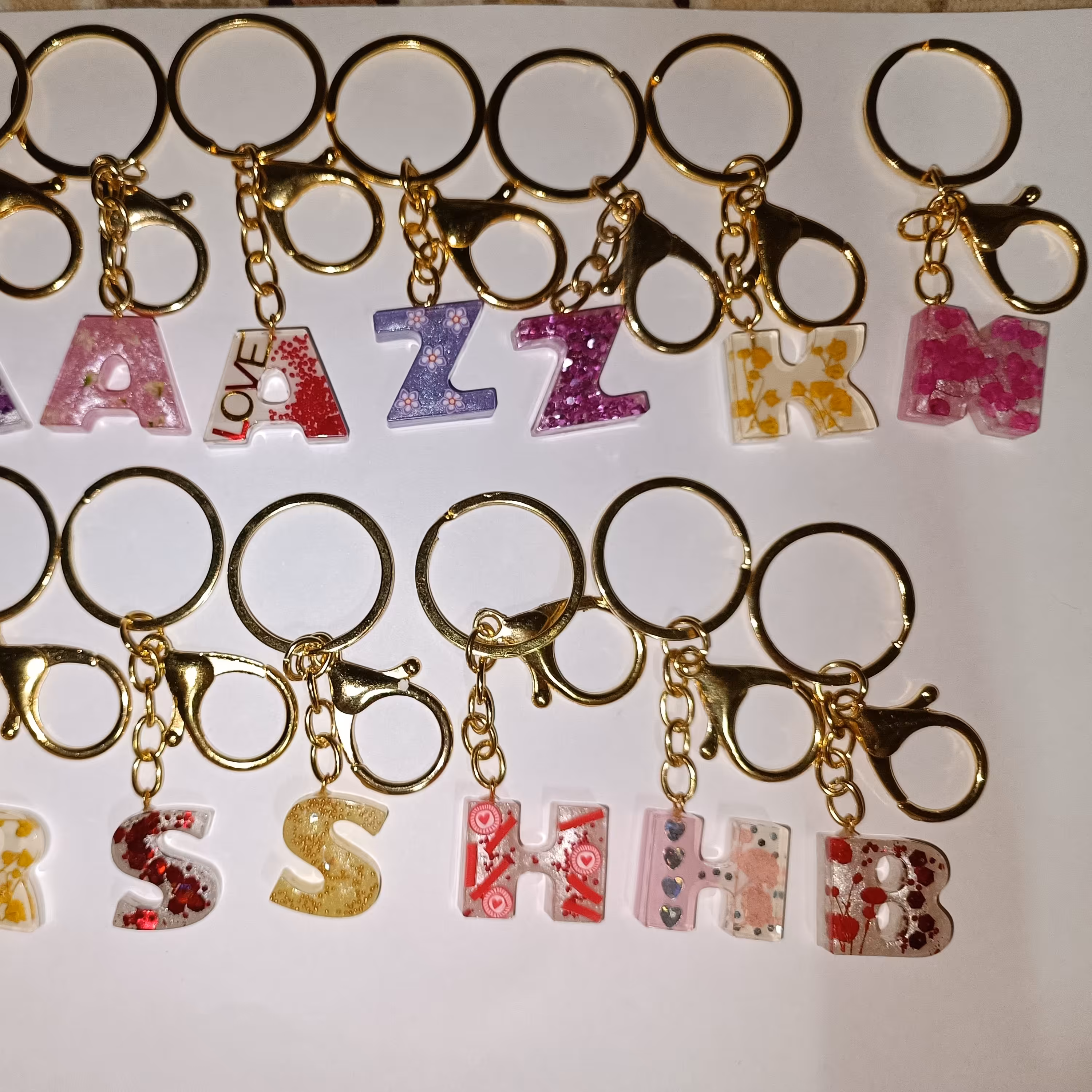 مجموعه 12 عددی سرکلیدی حروف انگلیسی به صورت عمده  با حروف انتخابی طرح و رنگ متنوع به صورت رندوم رنگ ثابت بدون حساسیت