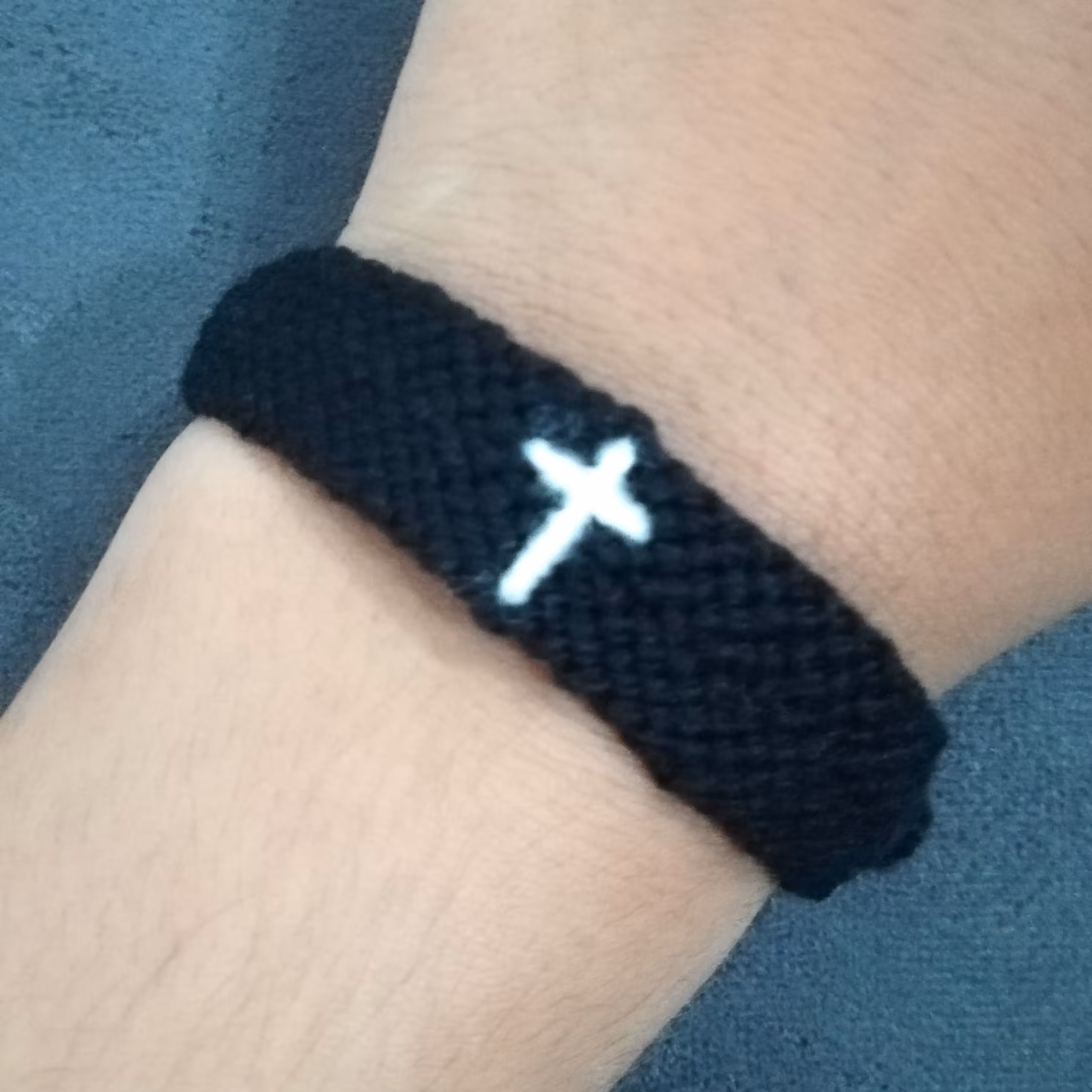دستبند دوستی بافتنی طرح سلیب سفید با پس زمینه مشکی 