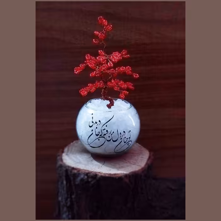 گلدان شیشه‌ای پر شده از سنگهای نمک و درختچه از جنس از سیم مسی بافته شده با منجق کریستالی قرمز  و متن شعر زیبا ،تمام کار 