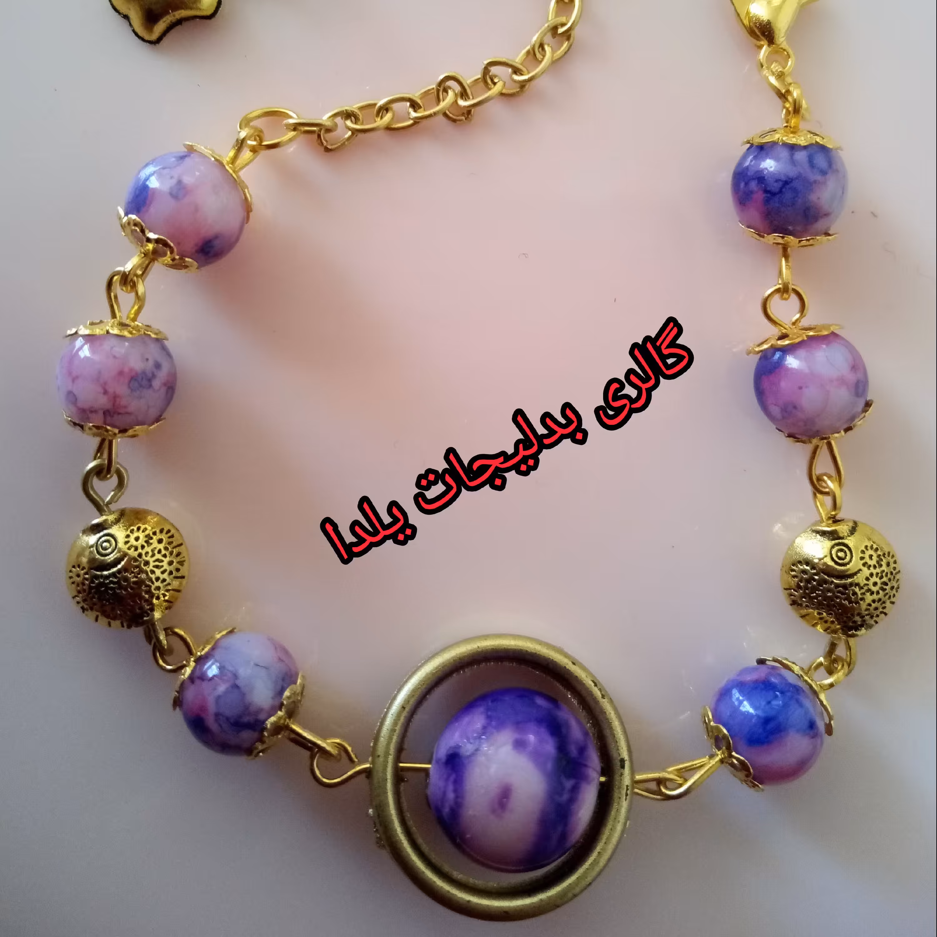 بدلیجات دستبند ماهی طلایی با خرج کار ماهی طلایی و مهره های سنگی آبرنگی بنفش و صورتی وزنجیر طلایی و آویز طرح سیب
