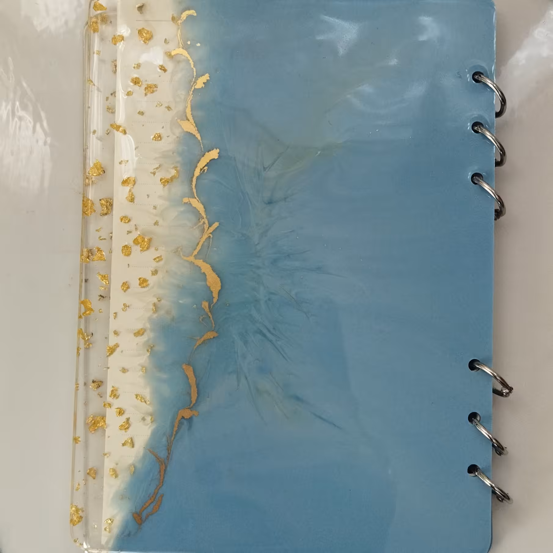 دفتر  رزینی، آبی رنگ با لبه های رزین شفاف به همراه ورقه طلا، 50 برگه با حلقه های بازشونده، قابل سفارش در هر رنگ و مدل