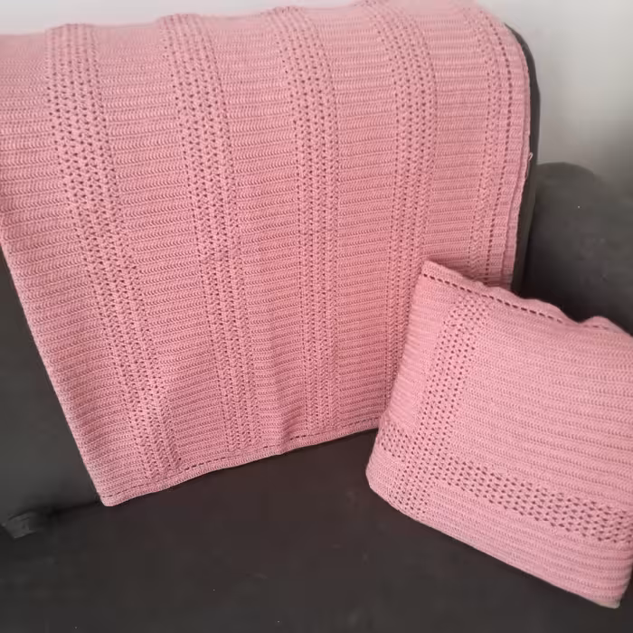شال مبل صورتی رنگ همراه با یک عدد رو کوسن بافته شده با نخ ترک