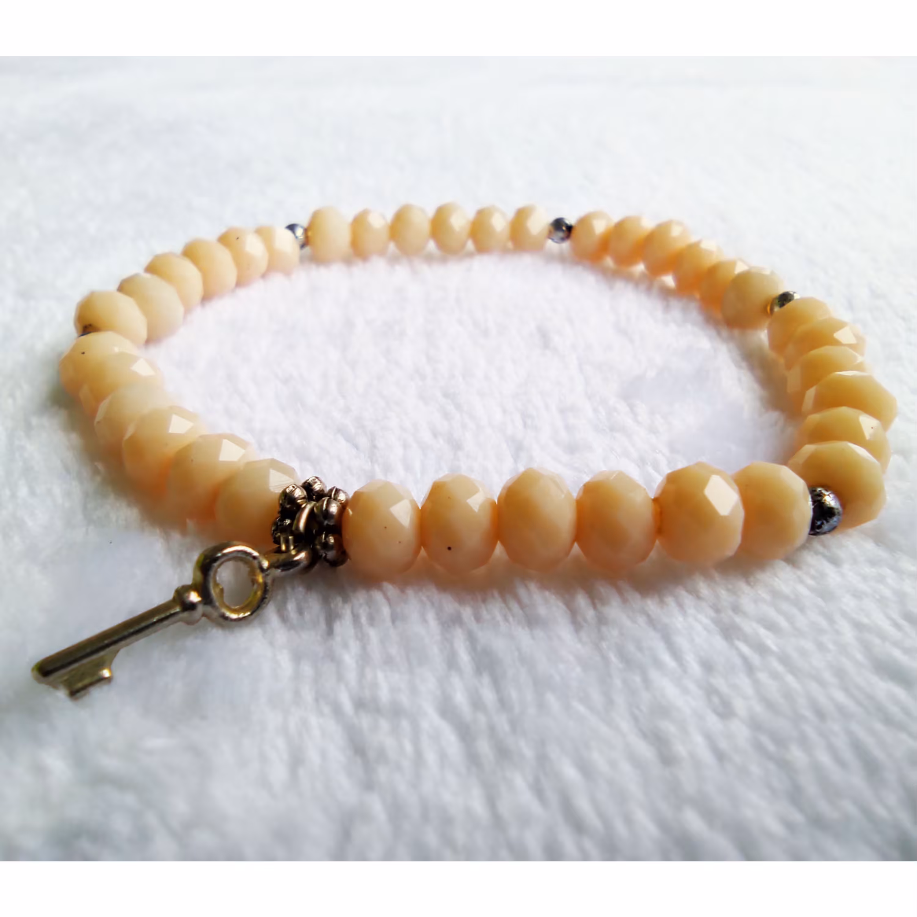 دستبند سنگ تراش خورده کرم صورتی با آویز کلید