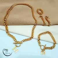 ست گردنبند و دستبند و انگشتر و گوشواره کارتیر  با آویز حروف لاتین جنس استیل(لاوین گالری)