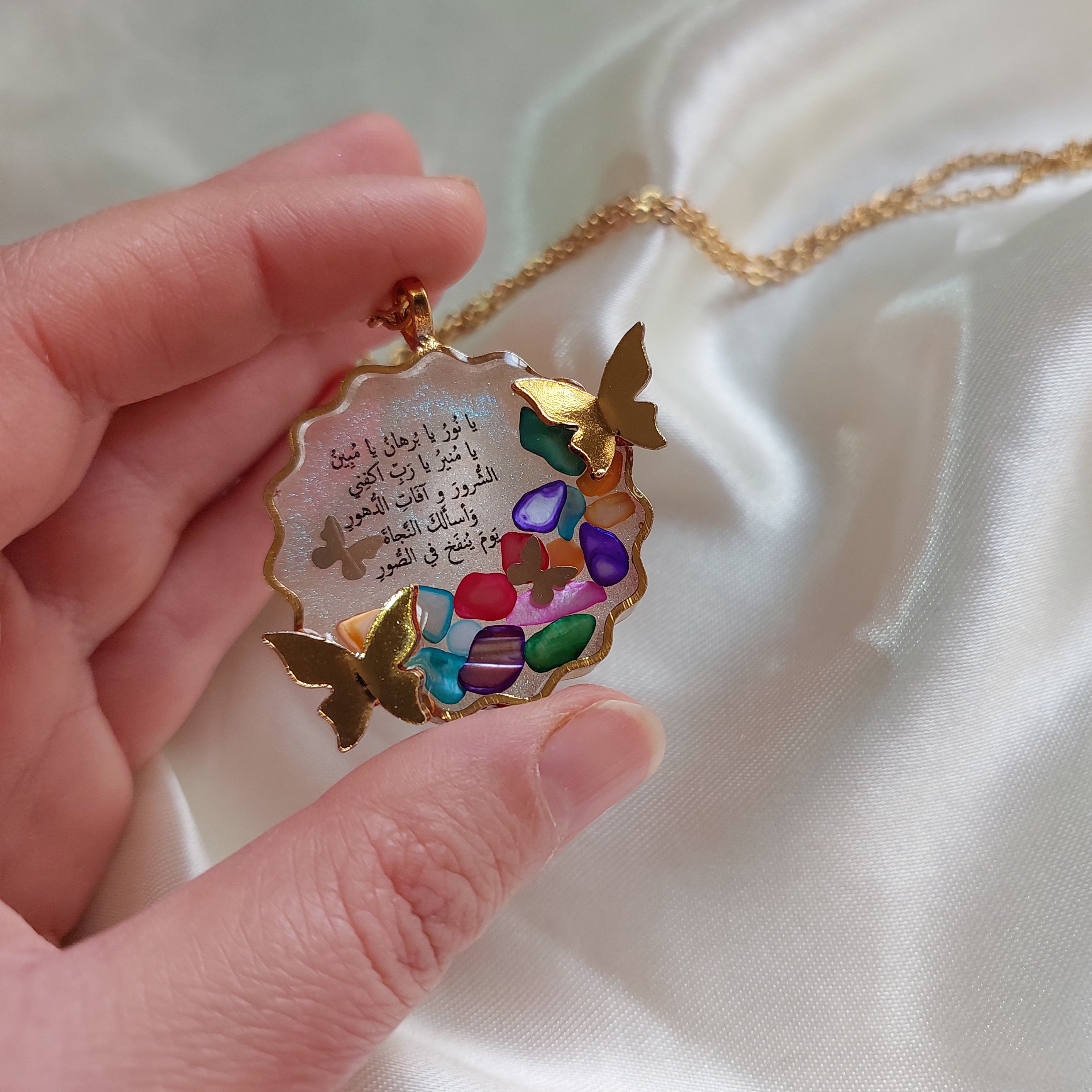 گردنبند رزینی حرز امام جواد(ع) قاب روکش استیل طلایی، یراق آلات رنگ ثابت با تزئین سنگهای زیبا و پروانه مینیاتوری