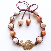 دستبند مدل بته جقه سنگ های عقیق رگه دار نارنجی کرم و پلاک استیل طرح بته جقه و بافت منحصر به فرد بین مهره ها