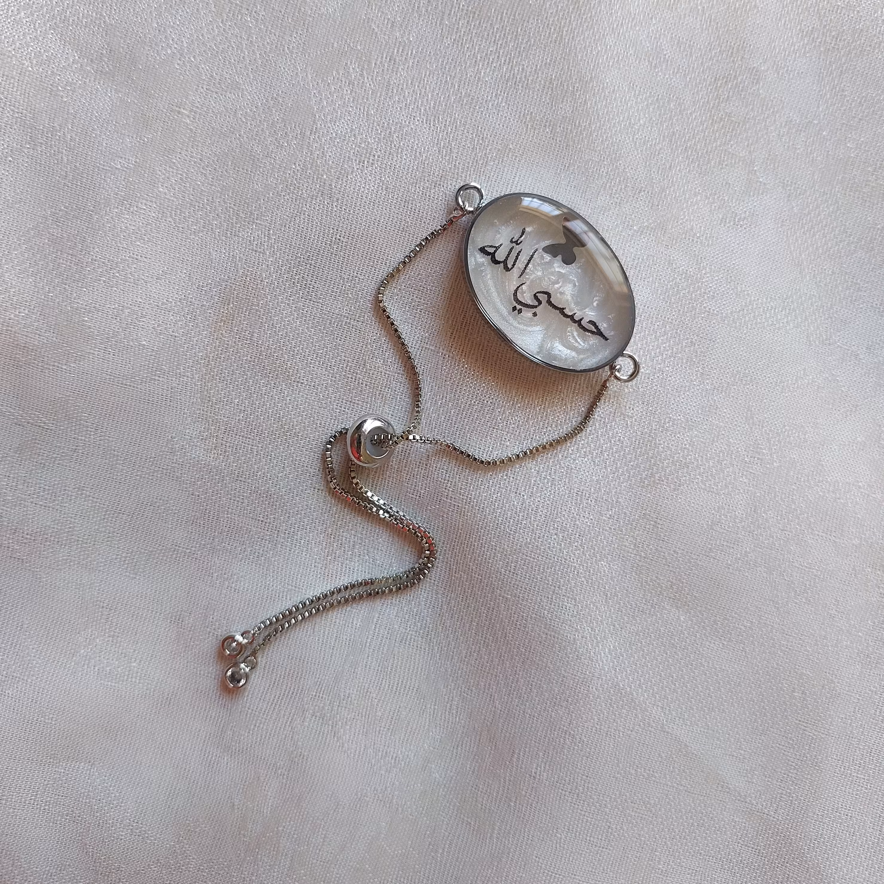 دستبند رزینی با نوشته حسبی الله قاب استیل نقره ای رنگ ثابت بهمراه زنجیر آسانسوری بسیار باکیفیت و رنگ ثابت