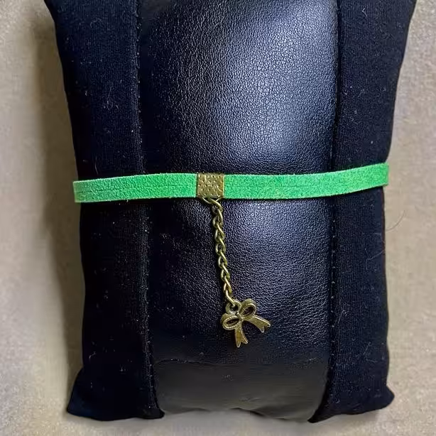 دستبند تریشه چرمی مدل ساده رنگ سبز همراه با خرج کار برنزی طرح پاپیون و تاج و زنجیر برنزی