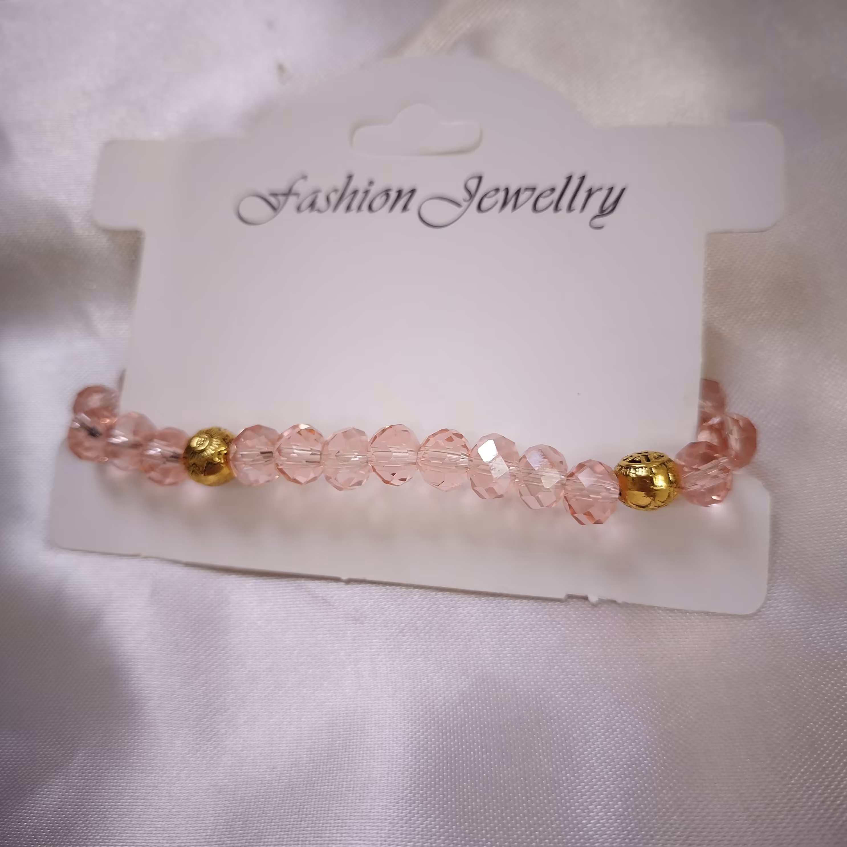 دستبند رنگ صورتی ملایم حدید طلایی که هردو طرف شکل داره