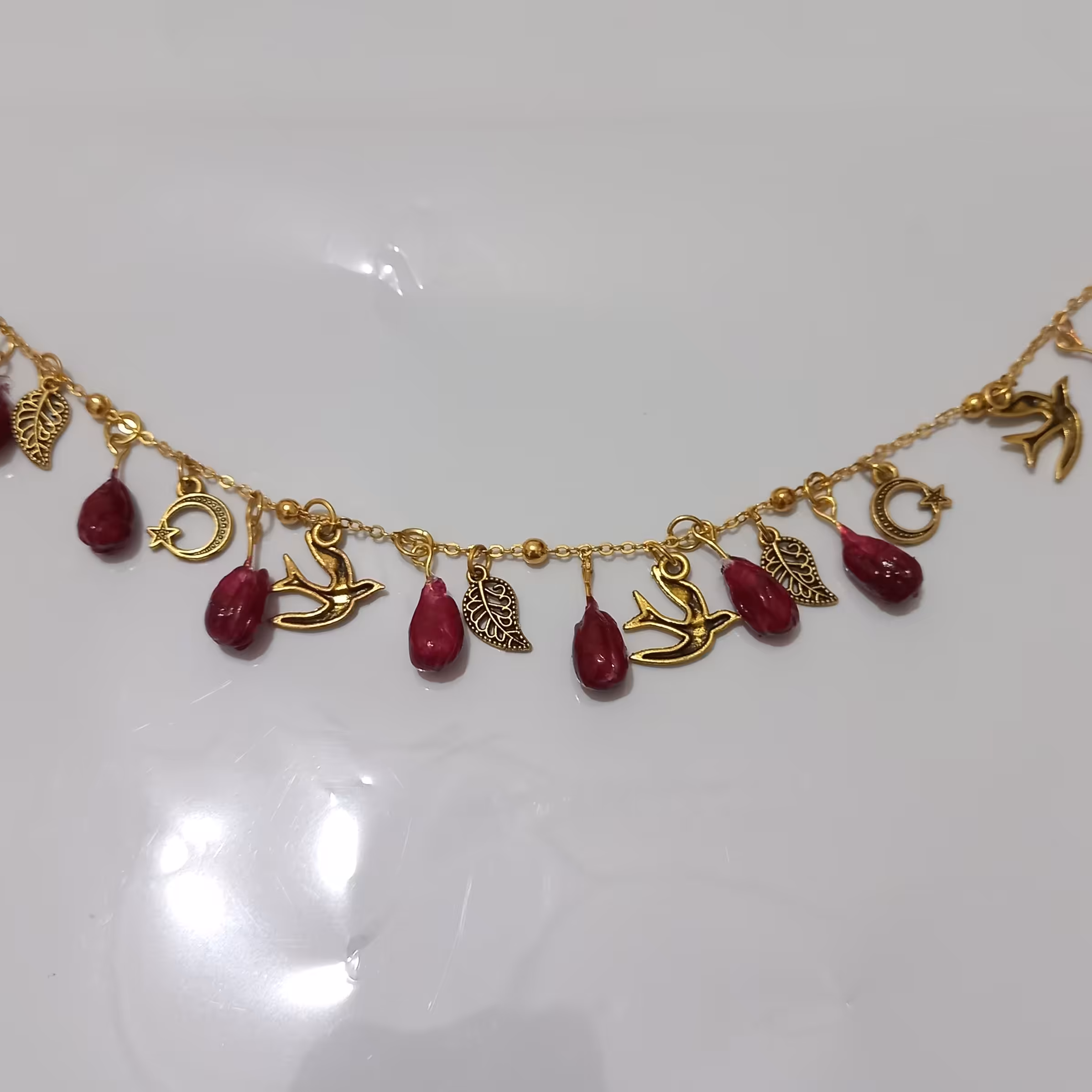 دستبند یلدا دستساز ، تزئین شده با دانه انار ، پرستو ، ماه ، برگ، زنجیر رنگ ثابت نیست