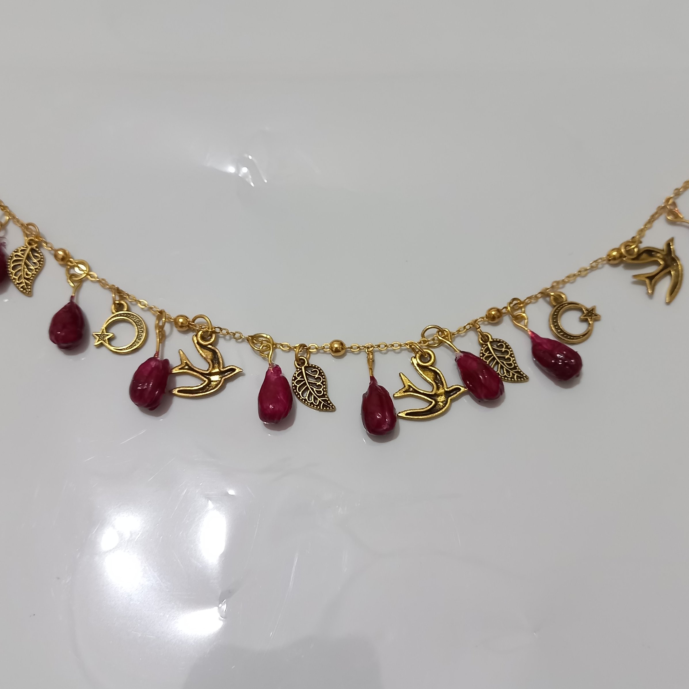 دستبند یلدا دستساز ، تزئین شده با دانه انار ، پرستو ، ماه ، برگ، زنجیر رنگ ثابت نیست