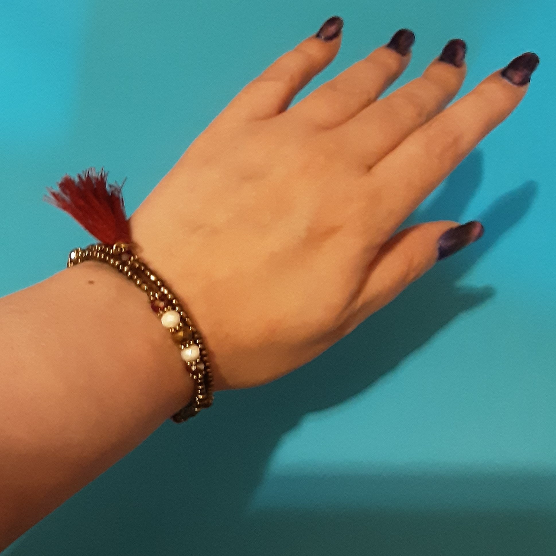 دستبند منگوله دار.2 دور.دارای سنگهای رنگ برنز به همراه کریستالهای چند وجهی دانه اناری.صدفی و برنزی رنگ.فری سایز