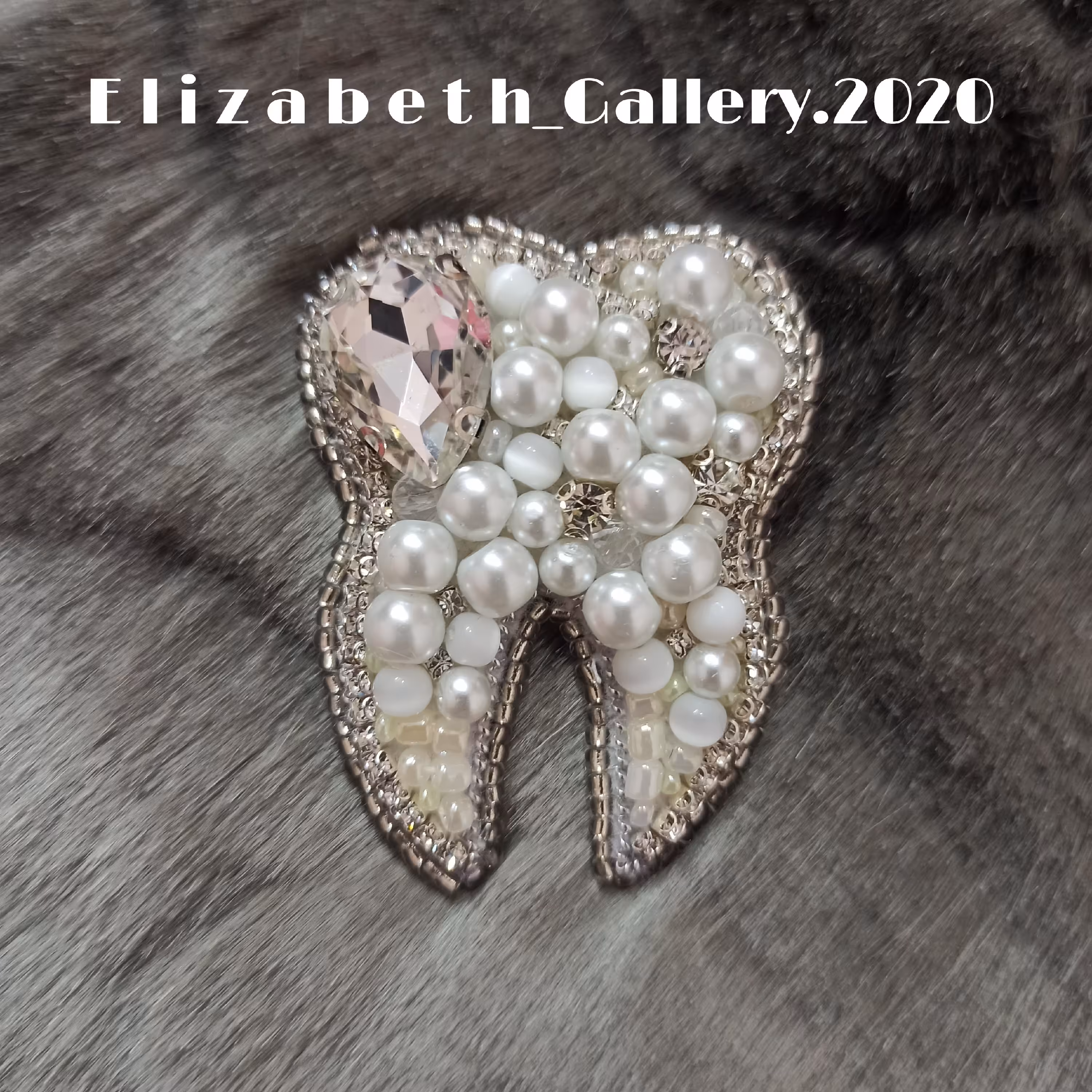 سنجاق سینه جواهر دوزی طرح(دندان)و پشت تماماً چرم و به رنگ سفید صدفی می‌باشد. 