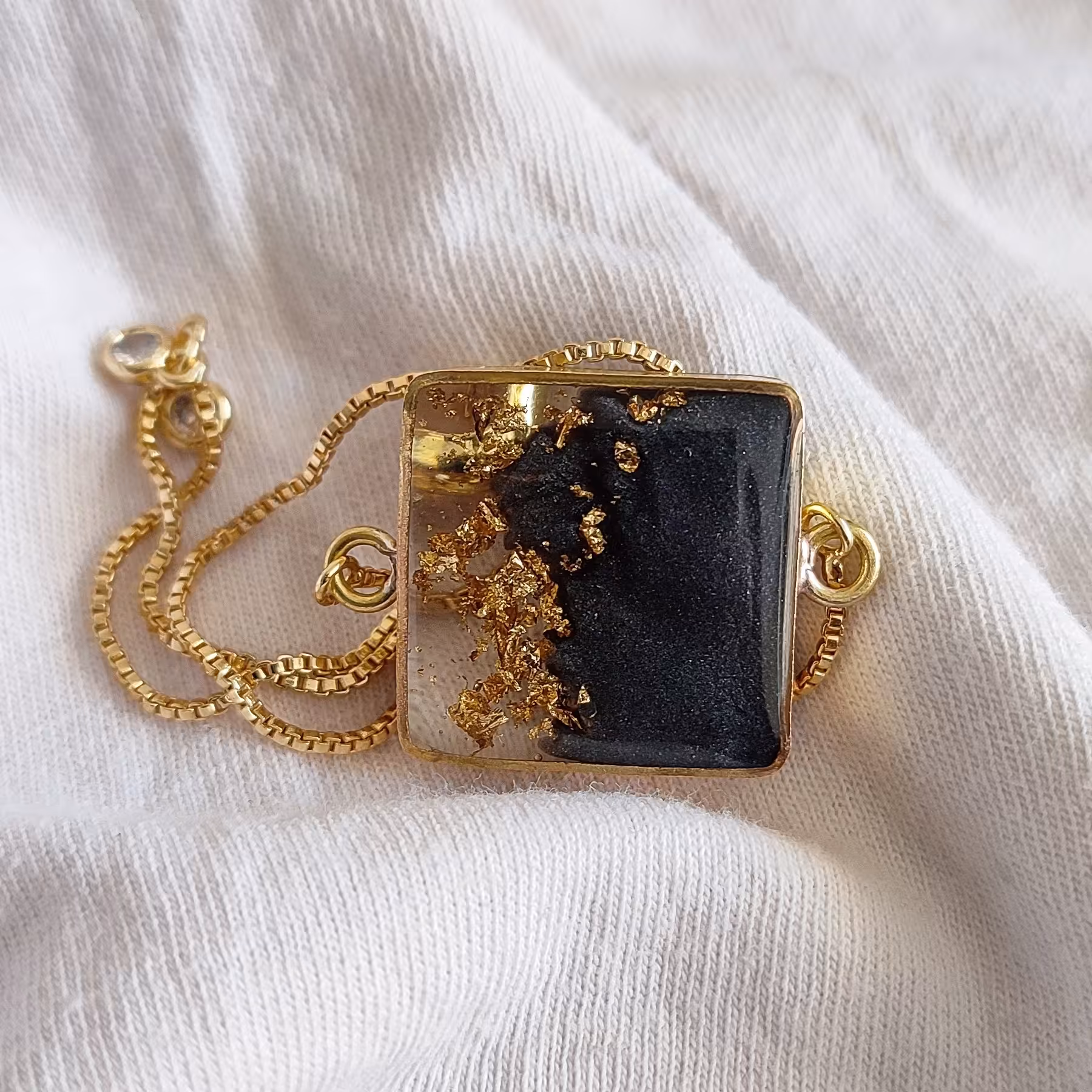 دستبند رزینی  صدفی سیاه با ورق طلا همراه دستبند اسانسوری قابل تنظیم 