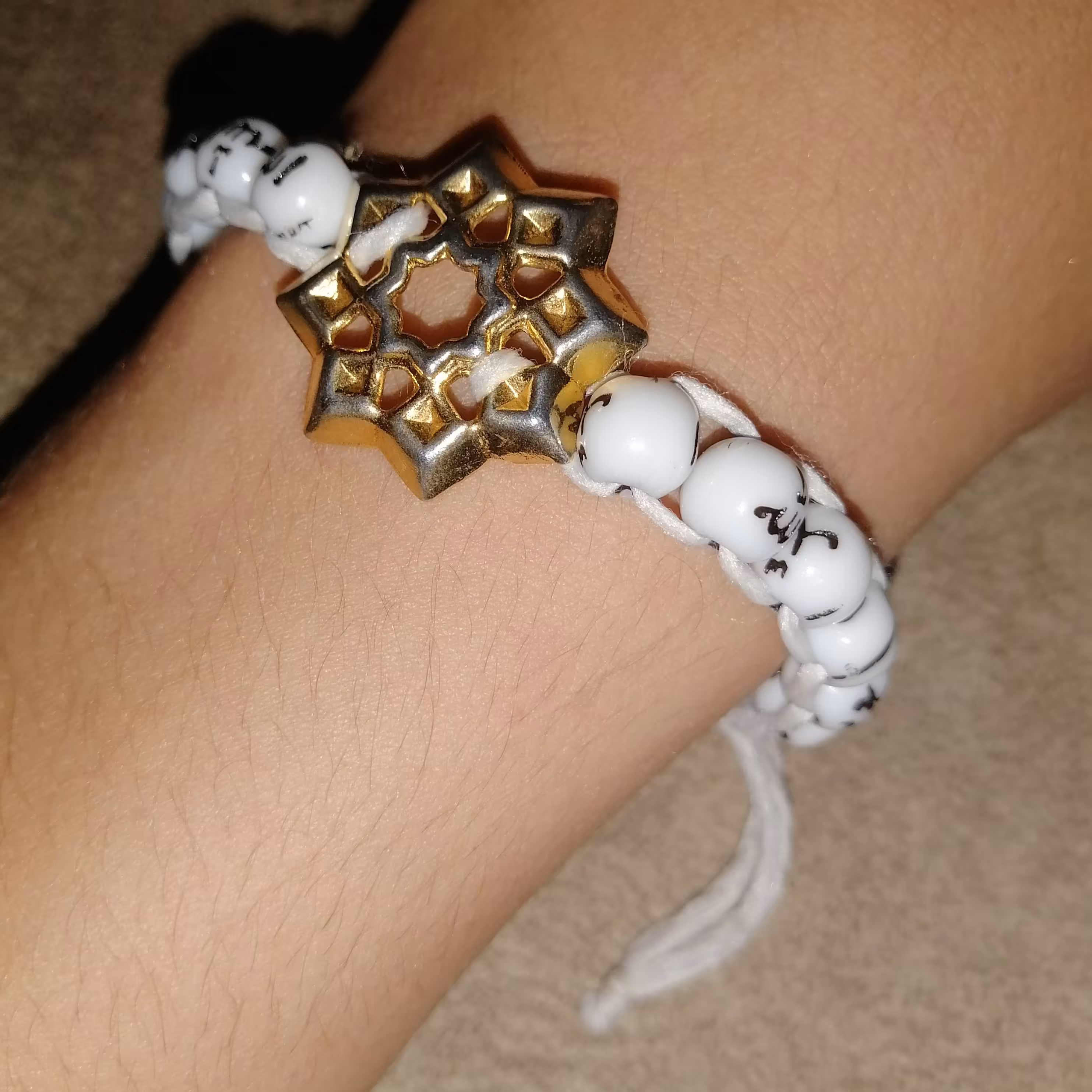 دستبند سیاه و سفیدی که در وسط آن ستاره زیبایی قرار دارد و... 