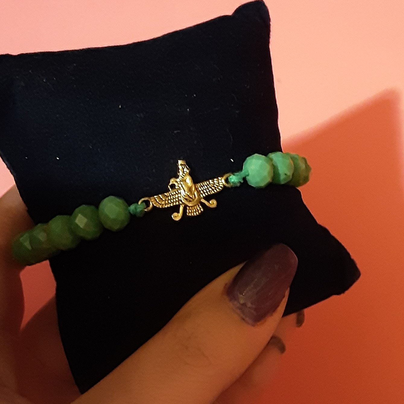 دستبند بافت.دارای کریستالهای تراش خورده به رنگ سبز اقیانوسی.به همراه پلاک برنزی طرح فروهر