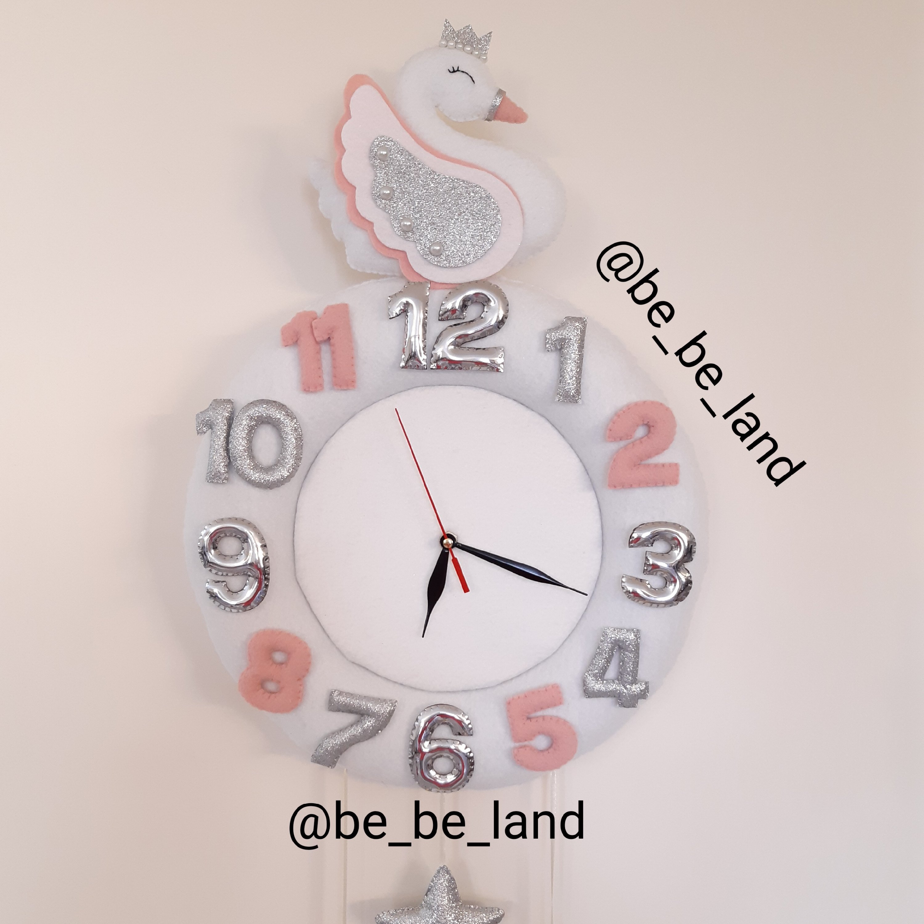 ساعت دیواری طرح قو رنگ سفید و نقره ای و صورتی ملایم جنس نمدی و موتور آرامگرد بدون صدای تیک تاک