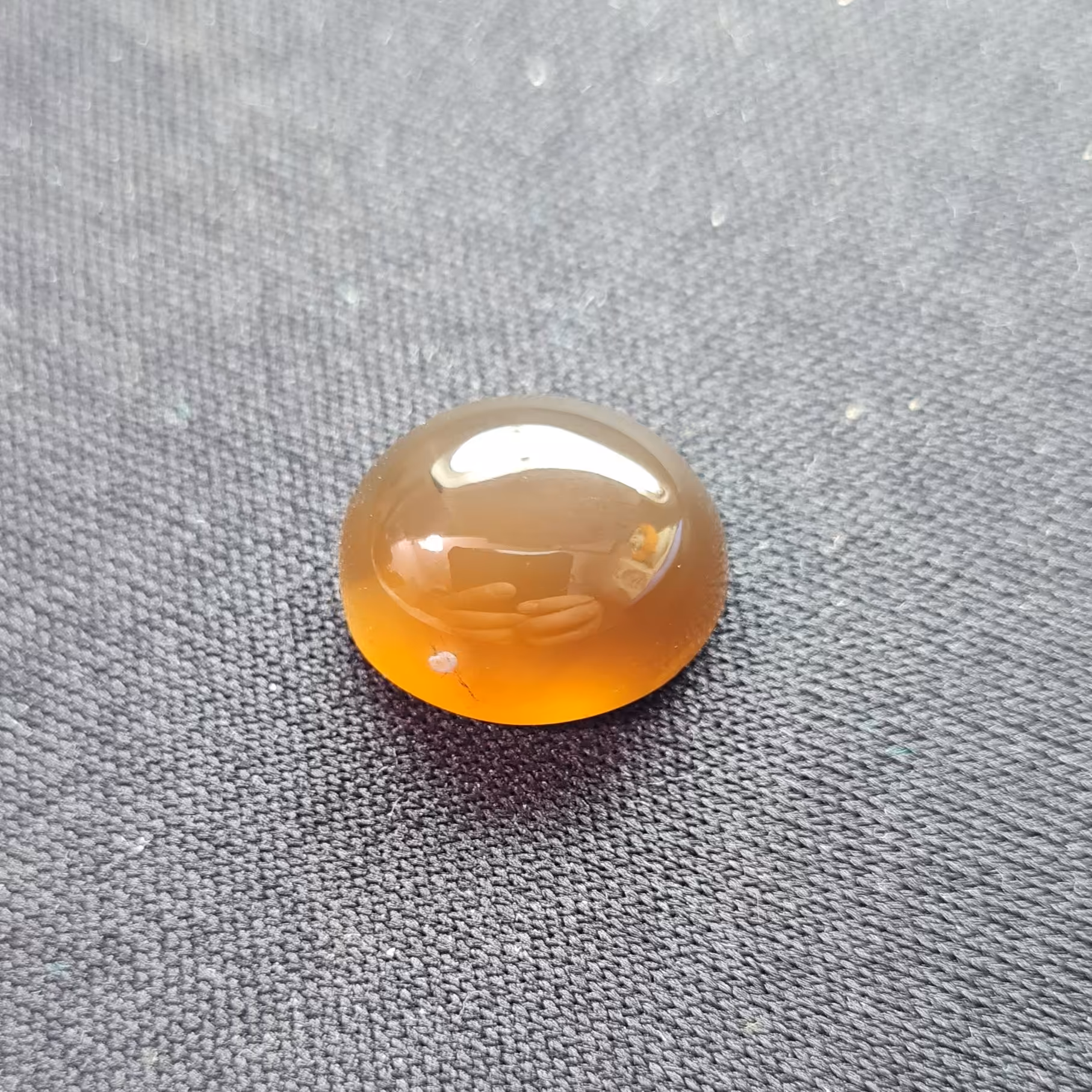 نگین عقیق خرمایی (مشخصات: طول: 1.4 سانتی متر. عرض: 1.1 سانتی متر. ارتفاع: 0.7 سانتی متر.)