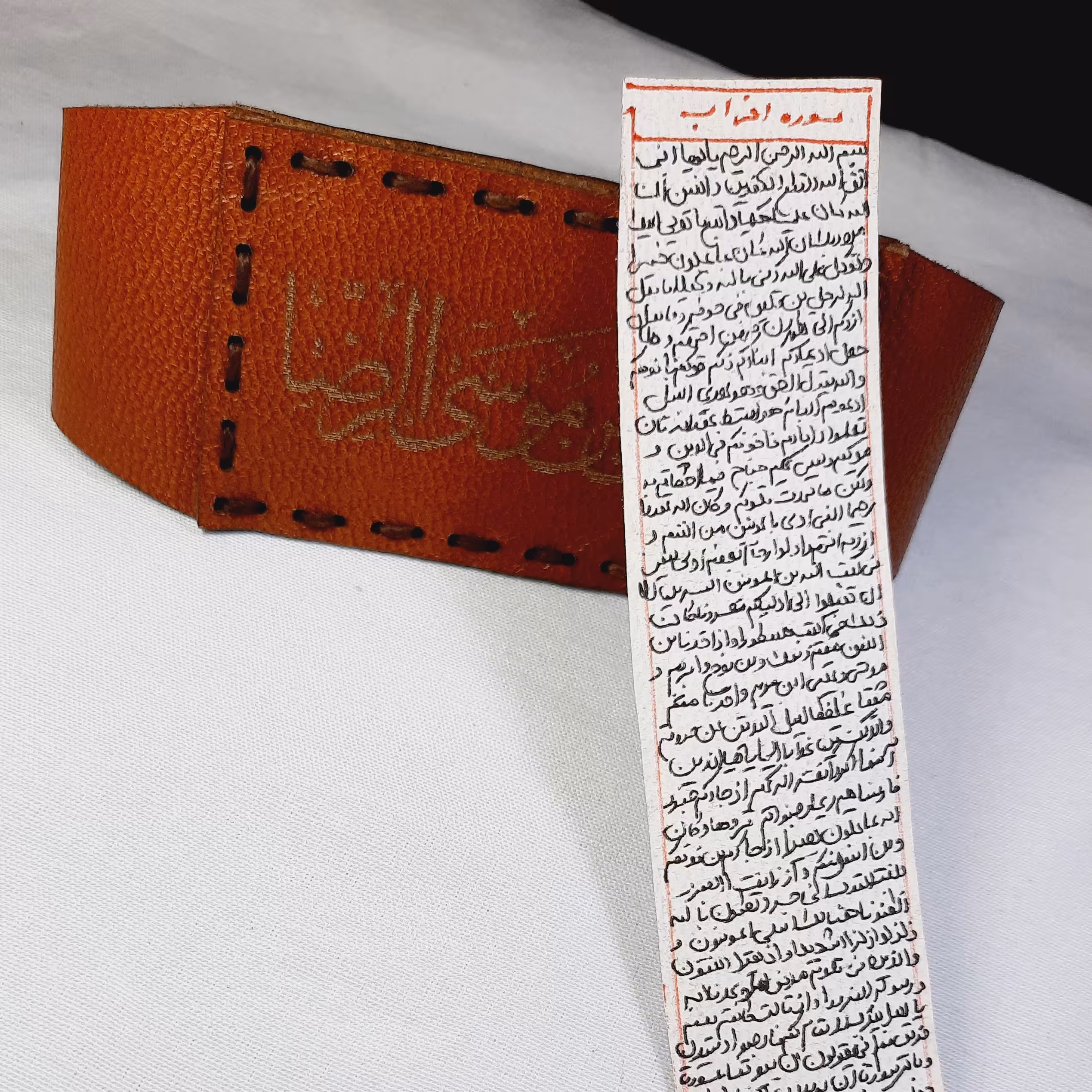 سوره مبارکه احزاب بر روی پوست آهو به صورت‌ خوش خط با بازوبند چرم طبیعی
