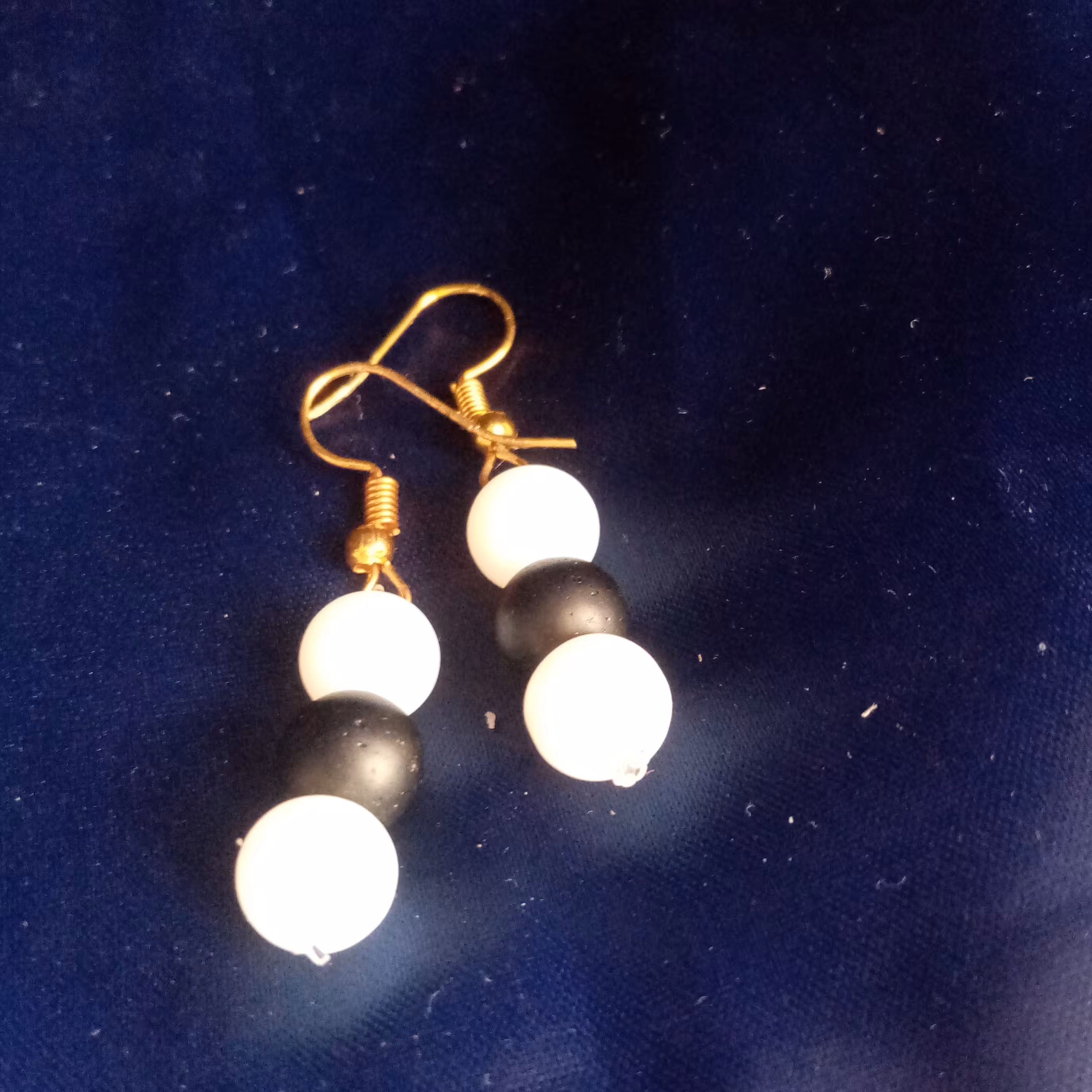 گوشواره سیاه سفید، این گوشواره ی زیبا با دسته ی طلایی و مهره های سیاه سفید درست شده 