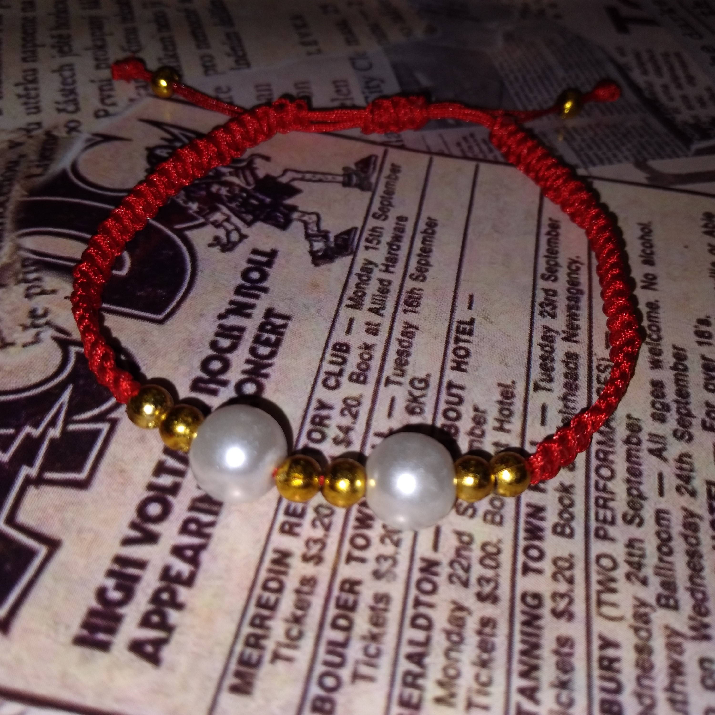 دستبند بافت قرمز با مهره سفید.