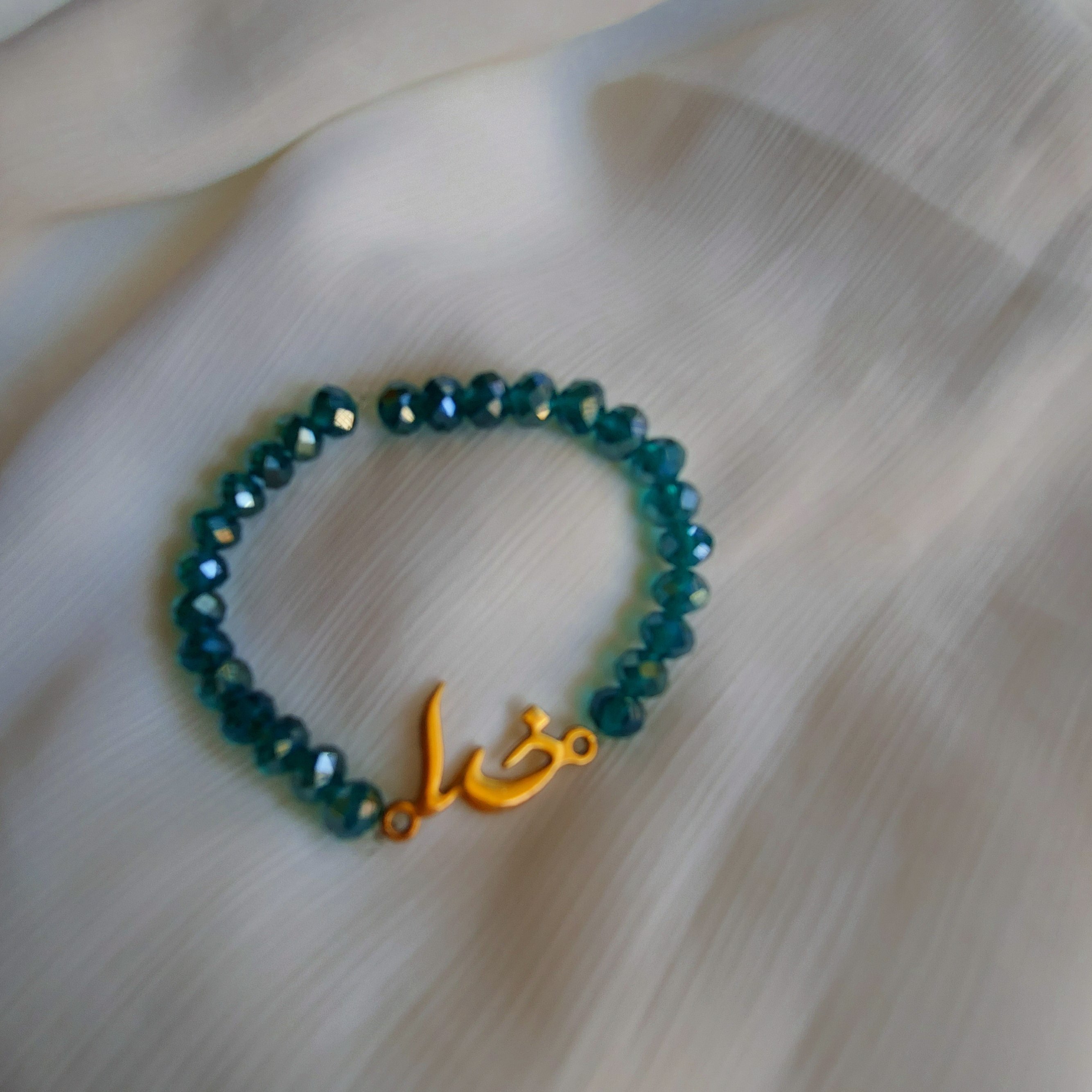 دستبند کریستالی مهره ای کشی رنگ سبز آبی تیره با پلاک رنگ ثابت (خدا) قابل سفارش با قفل