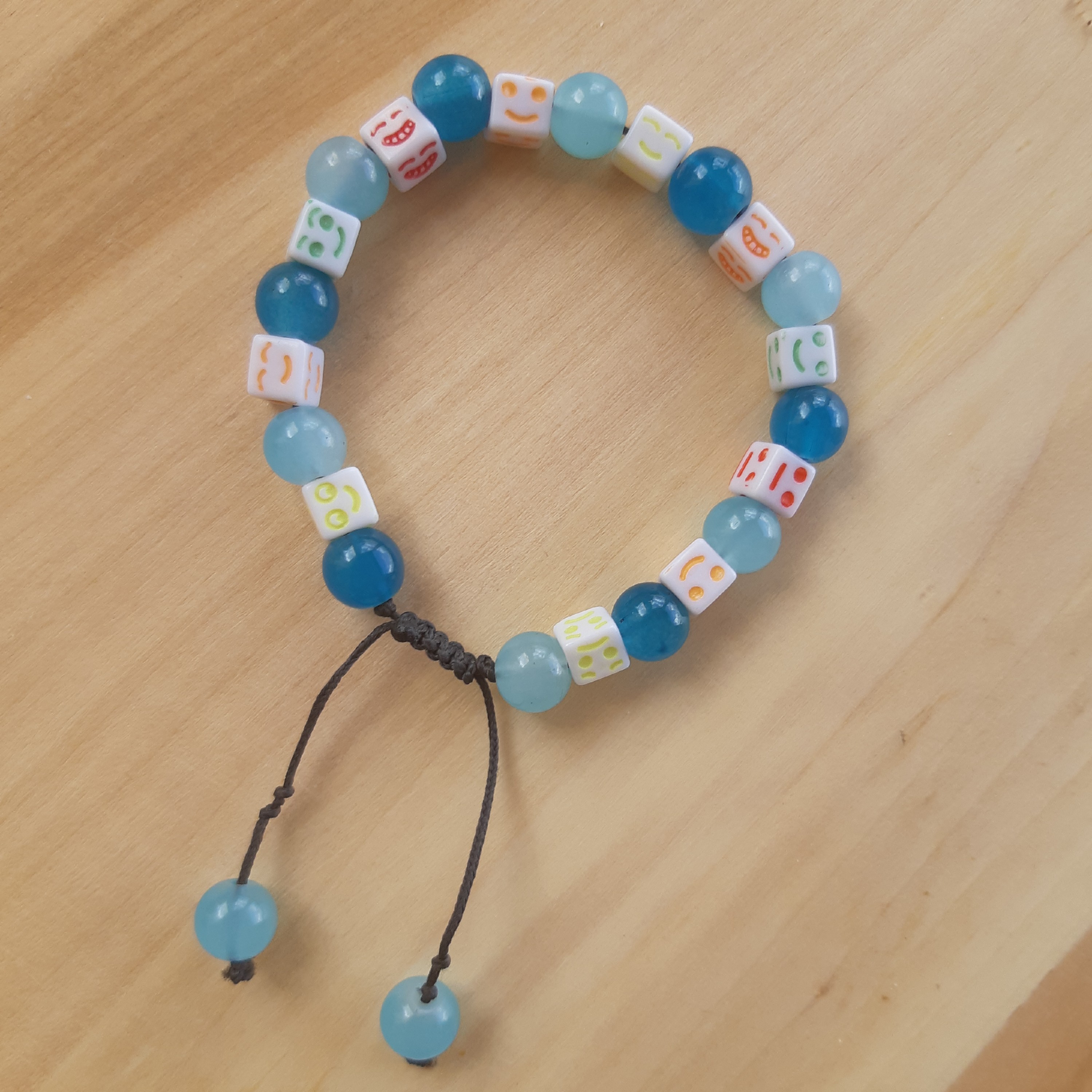 دستبند با مهره سنگی آبی روشن و سیر و مهره شکلک خندان رنگارنگ. با قفل کشویی(اندازه قابل تنظیم)