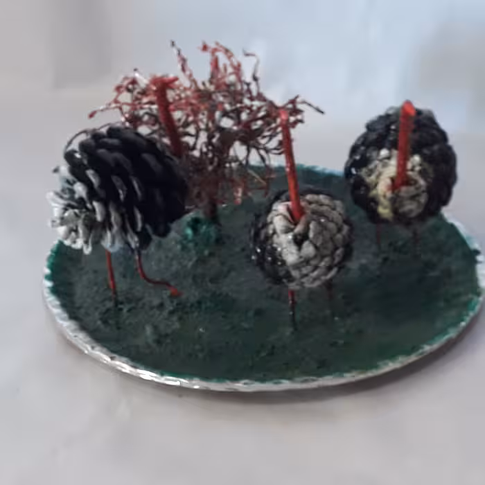 شتر مرغ با استفاده از گلهای خشک شده درخت کاج ، با رنگ روغن تزئین شده و محیط آن از مصنوعات پلاستیک استفاده شد (پس کرایه)