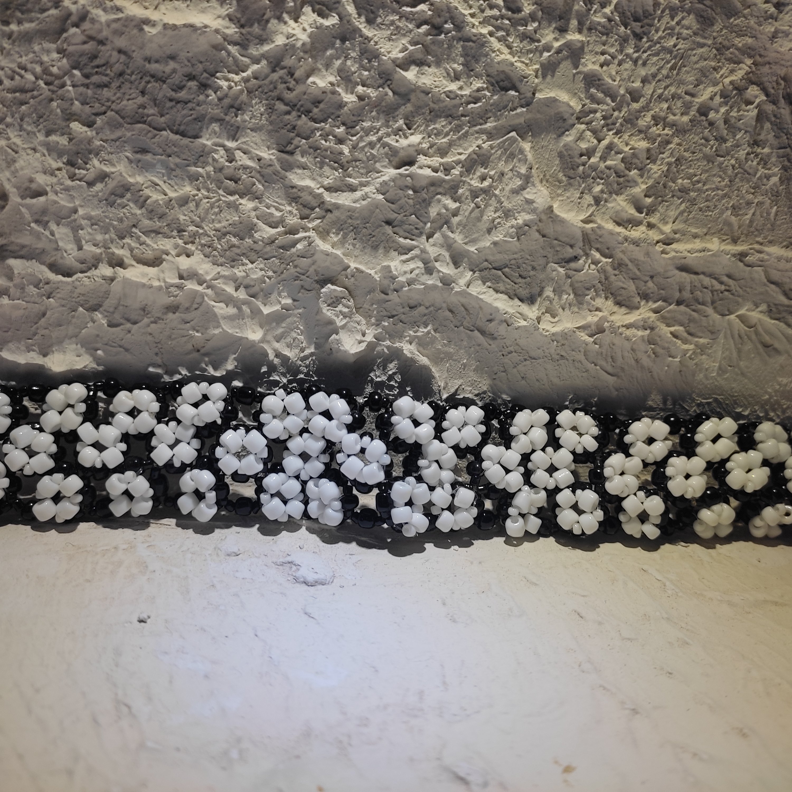 دستبند منجوق دوزی شده طرح گل سفید با پس زمینه مشکی پهن