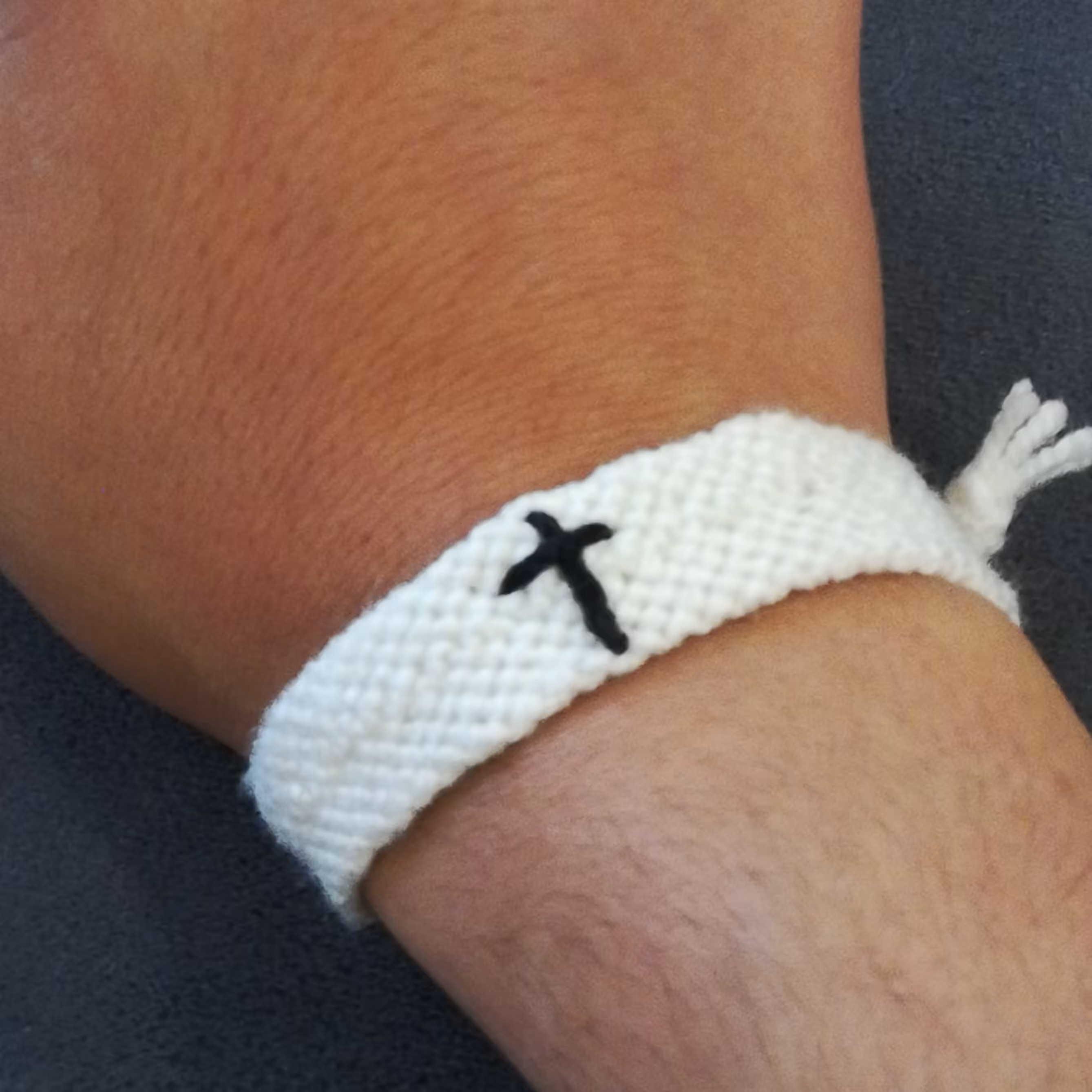 دستبند دوستی بافتنی طرح سلیب مشکی با پس زمینه سفید