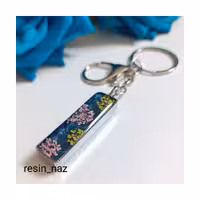 سرکلیدی و آویز کیف شیک استیل رزینی رنگ ثابت و ضدحساسیت نقره ای رنگ دوطرفه با گل شوکران و پولک صورتی شبتاب زمینه سرمه ای