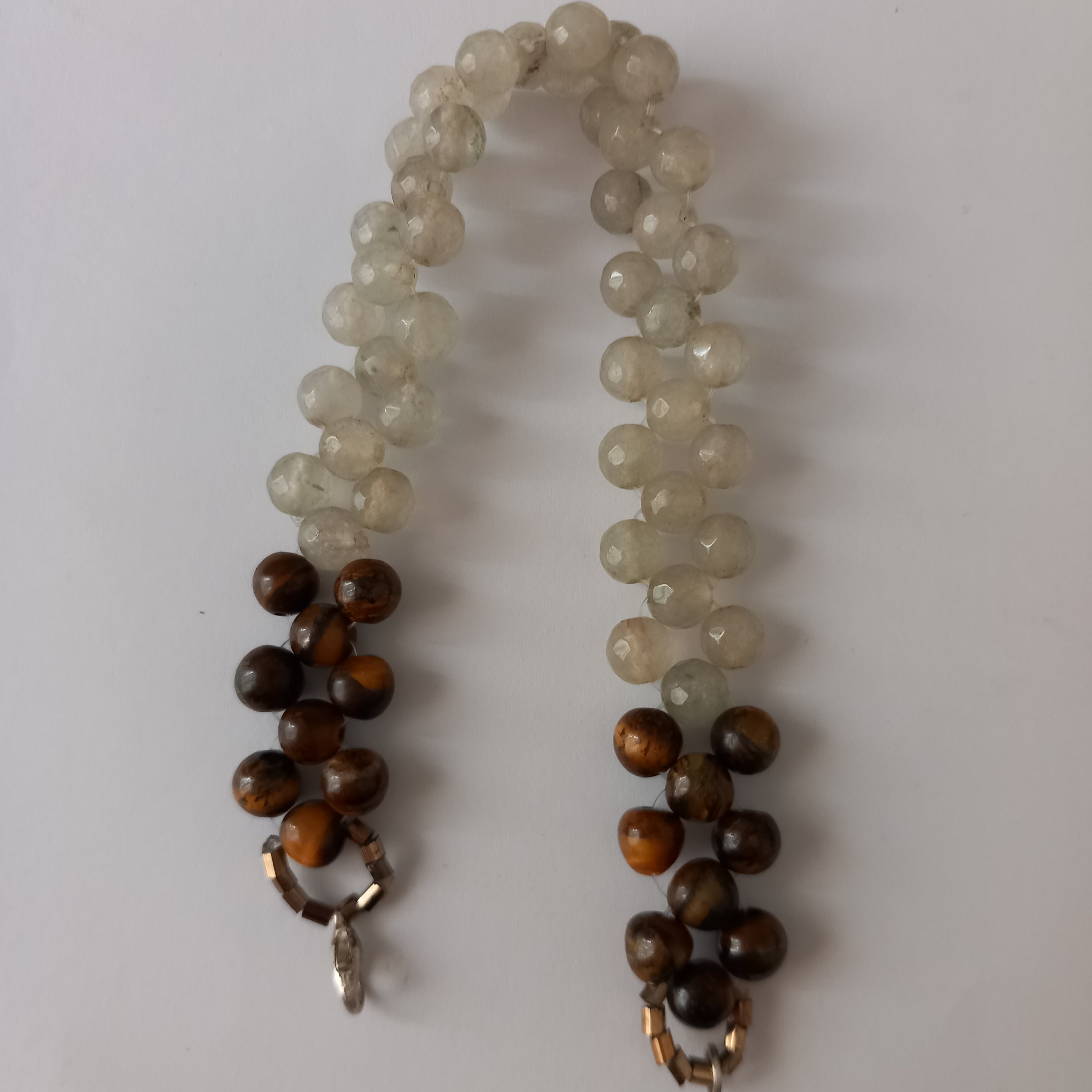 دستبند جید سفید رنگ که ابتدا وانتهایی آن باسنگ چشم گربه ای قهوه‌ای کار شده