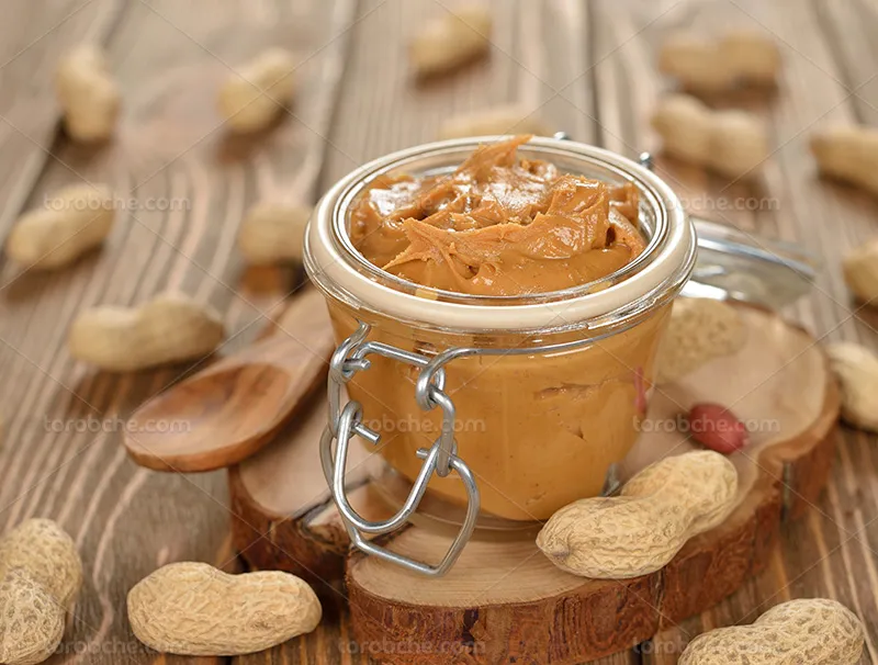 عکس کره بادام زمینی روی میز چوبی | گرافیک با طعم تربچه