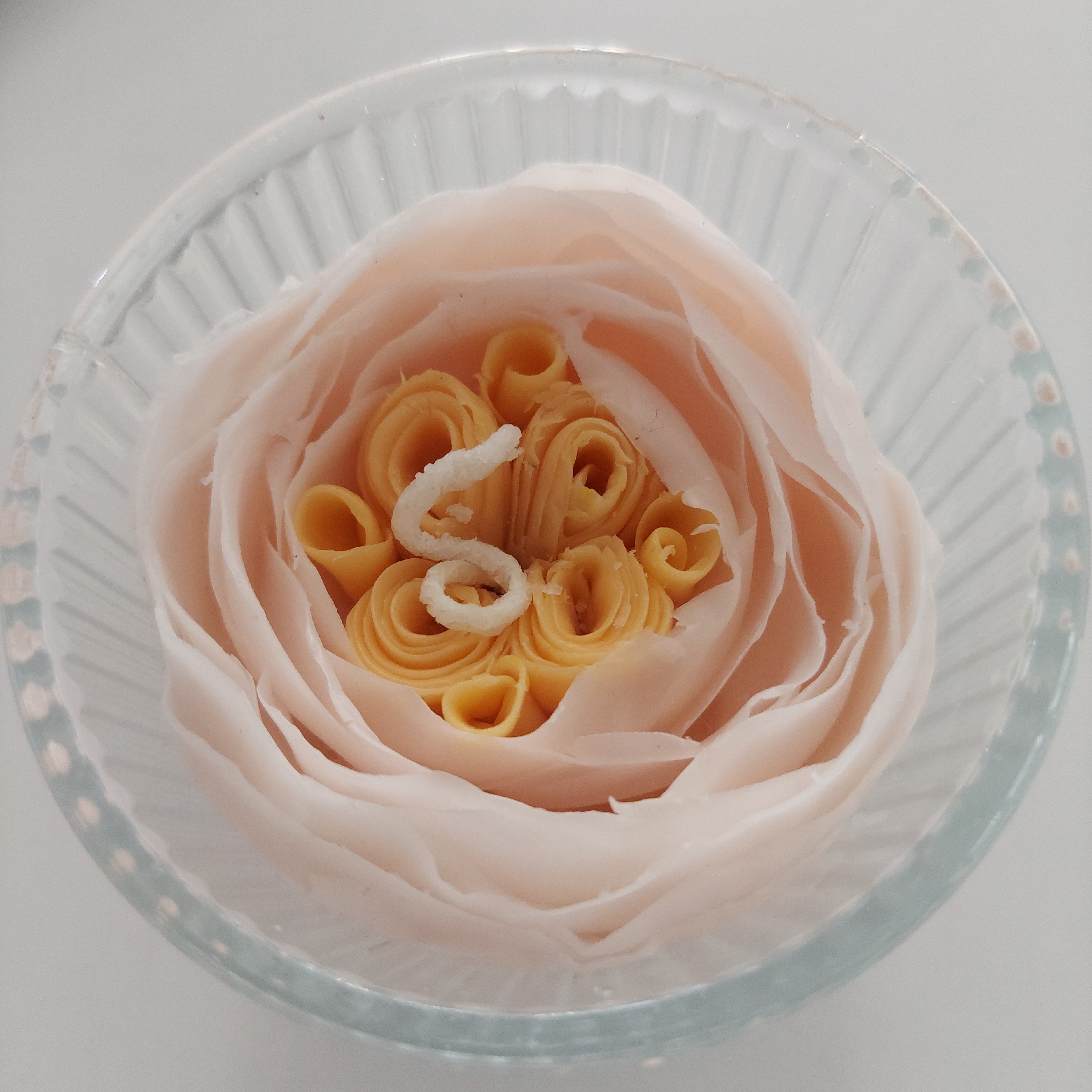 شمع گل دست ساز  رنگ صورتی ملایم و مغزی نارنجی روشن داخل شات شیشه ای راه راه